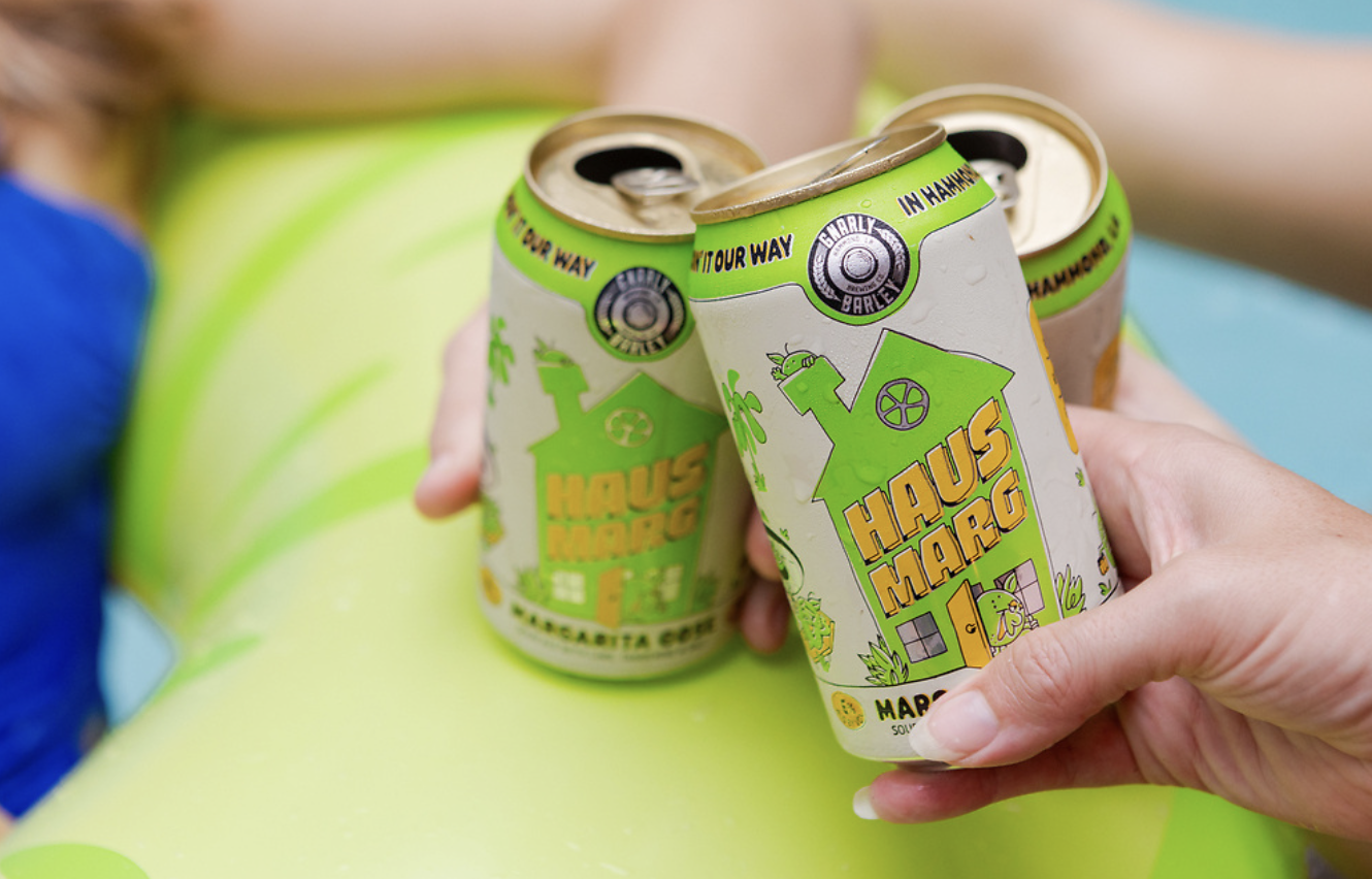 Two green canned margs being drank in a pool