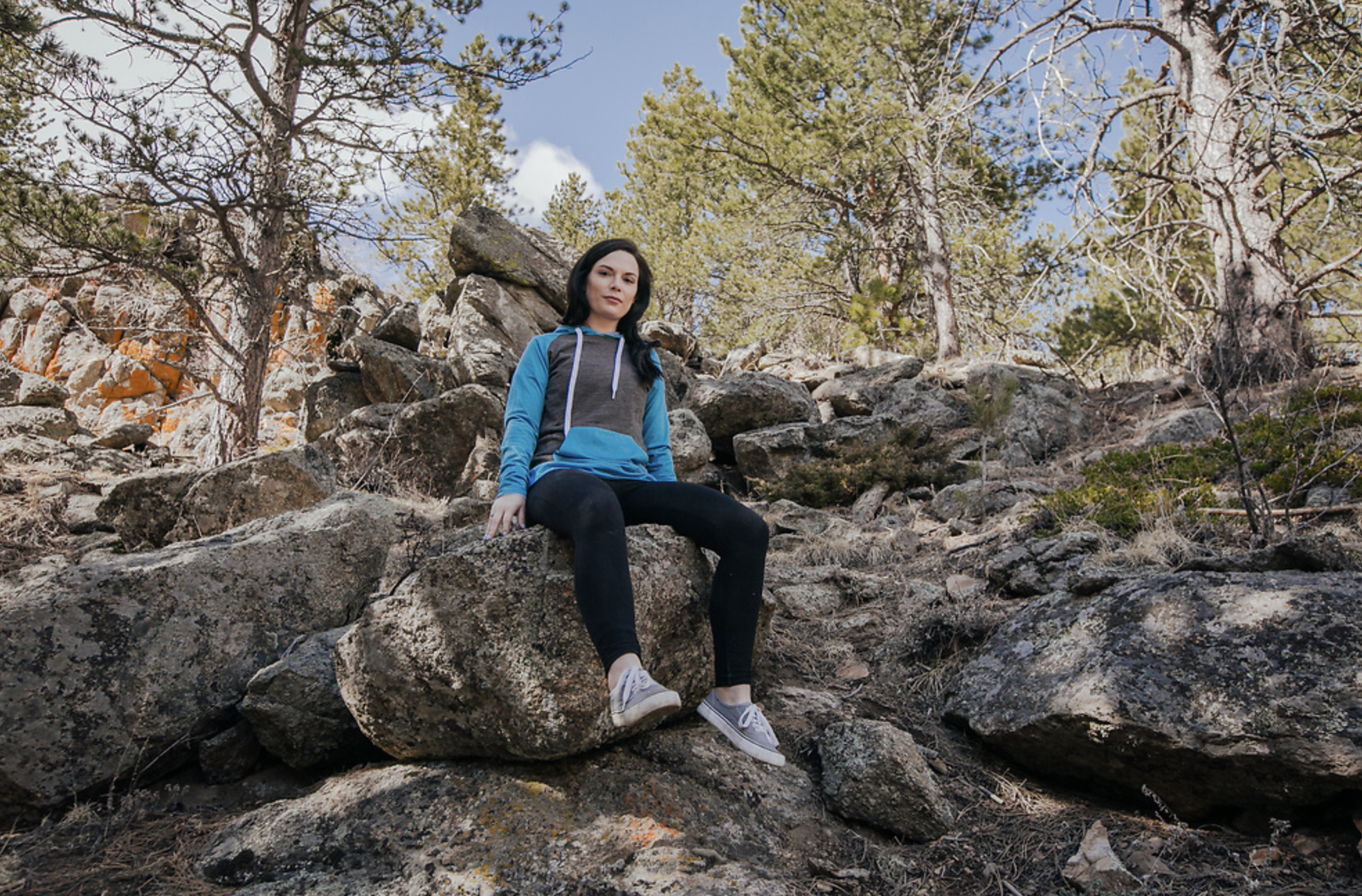 woman poses on rock in belong designs hoodie