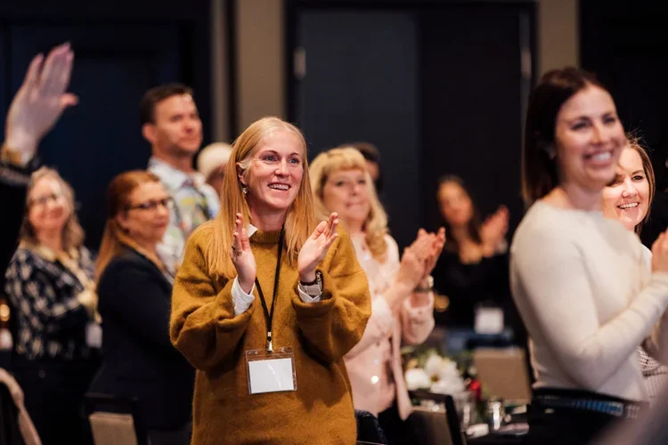 People stand and clap at the national corporate housing conference