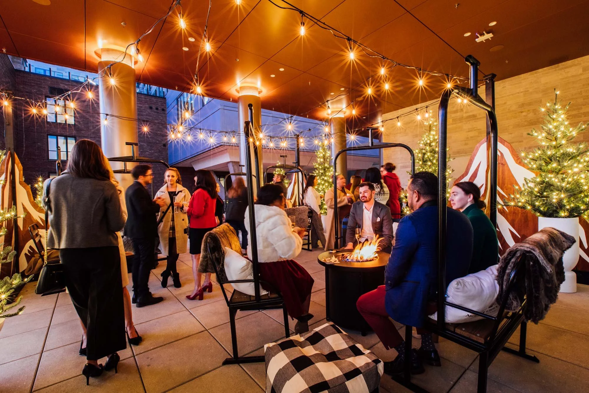 Groups stand and sit around fires at Kimpton Claret Hotel Holiday event