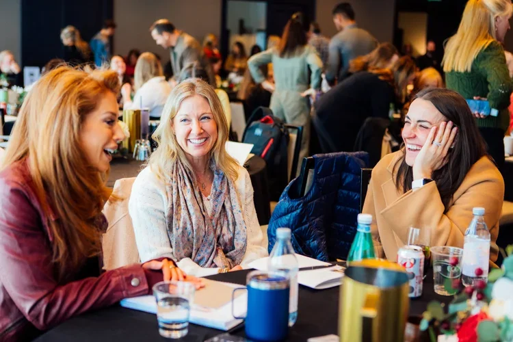 Three women sit and laugh together during small groups at 8Z Con