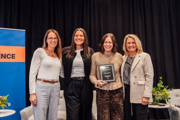 four women pose together after one has won an award at the national corporate housing conference