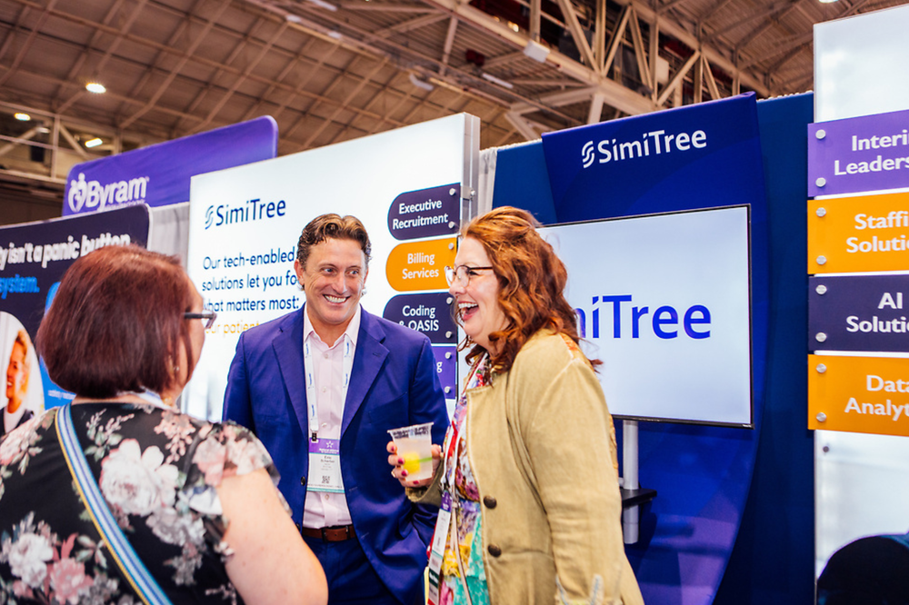 two women and a man laugh together at the simitree booth at the national alliance for care at home expo