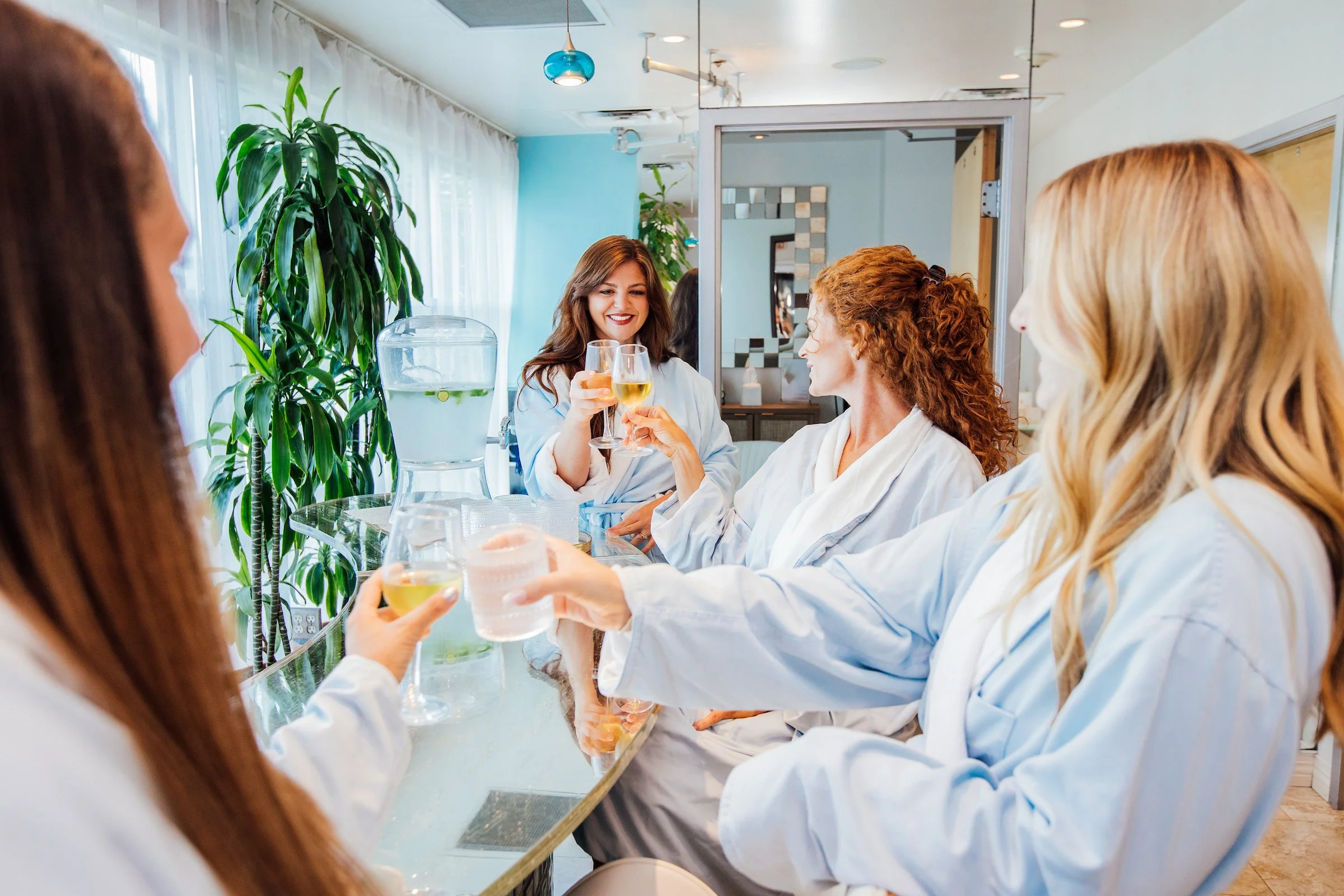 Four women toast with wine in robes at the O Spa