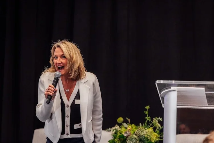 Woman smiles as she speaks into a microphone at the national corporate housing conference