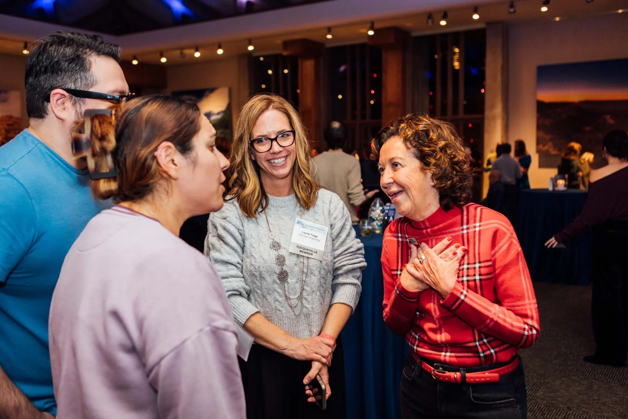 Group of four smile together at company holiday event