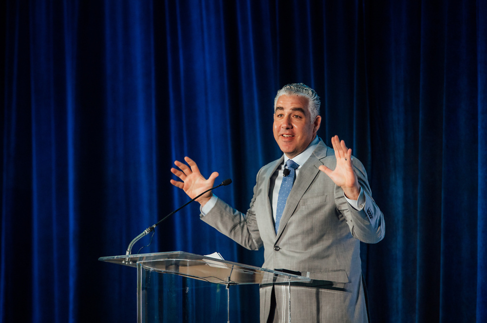 man on a stage smiles as he presents at the national alliance for care at home conference