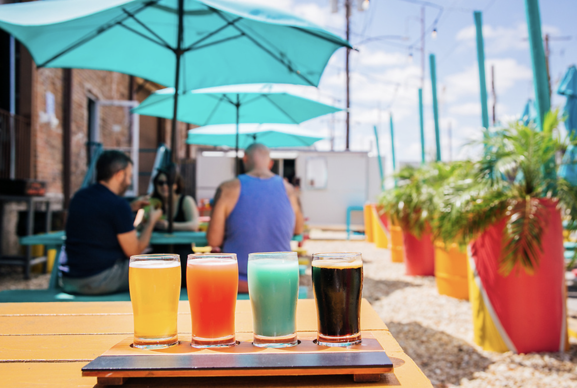yellow, pink, green and black beer in a flight at a brewery