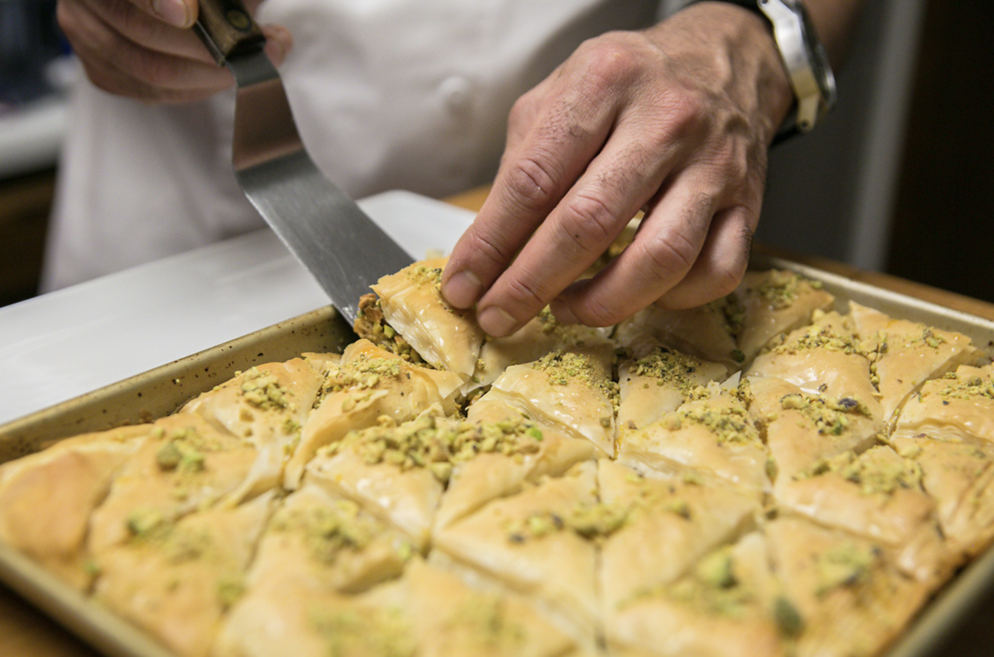 a chef cuts a piece of pistachio balaclava