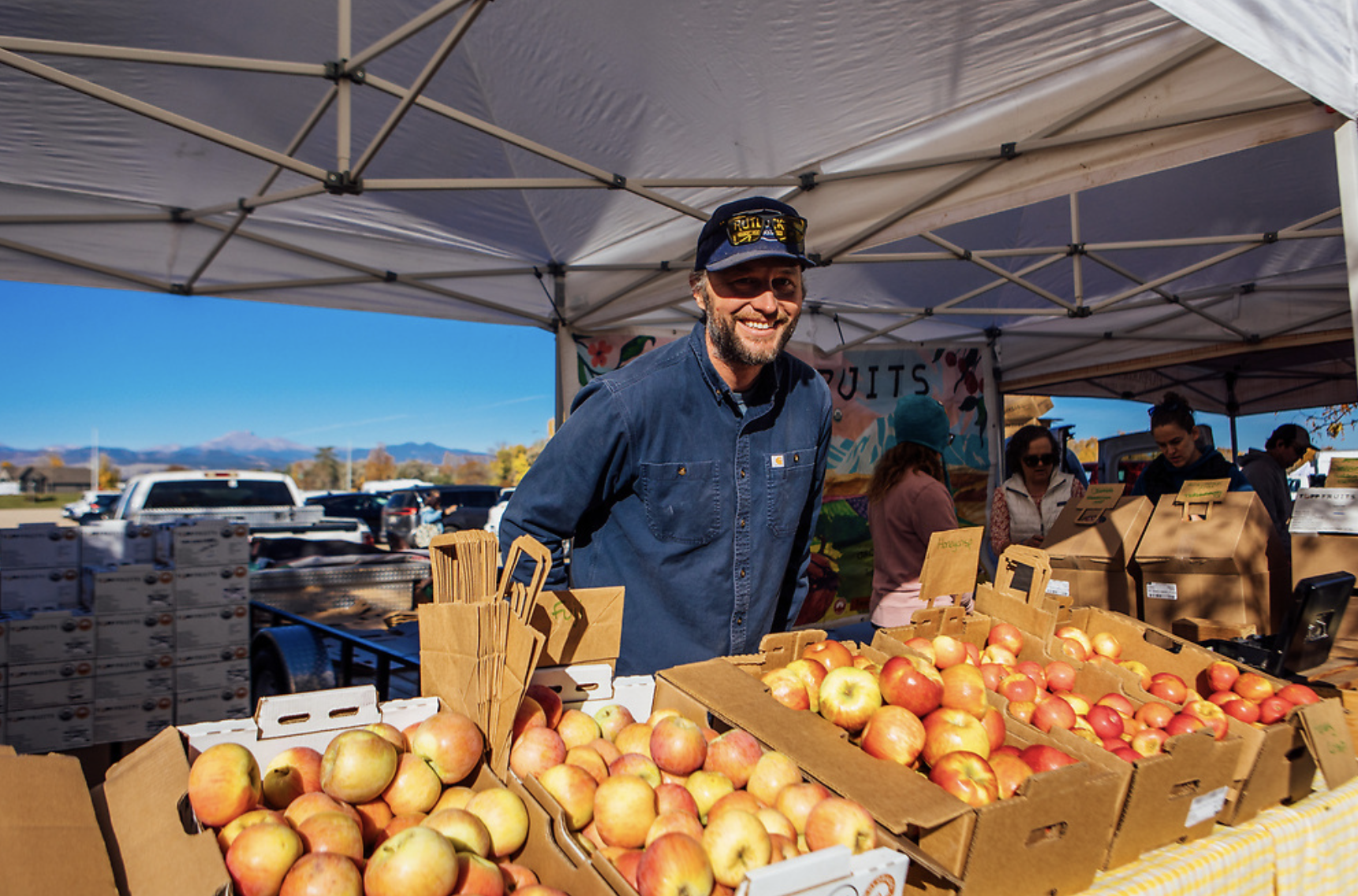 Farmer poses with apples he is selling at farmers market