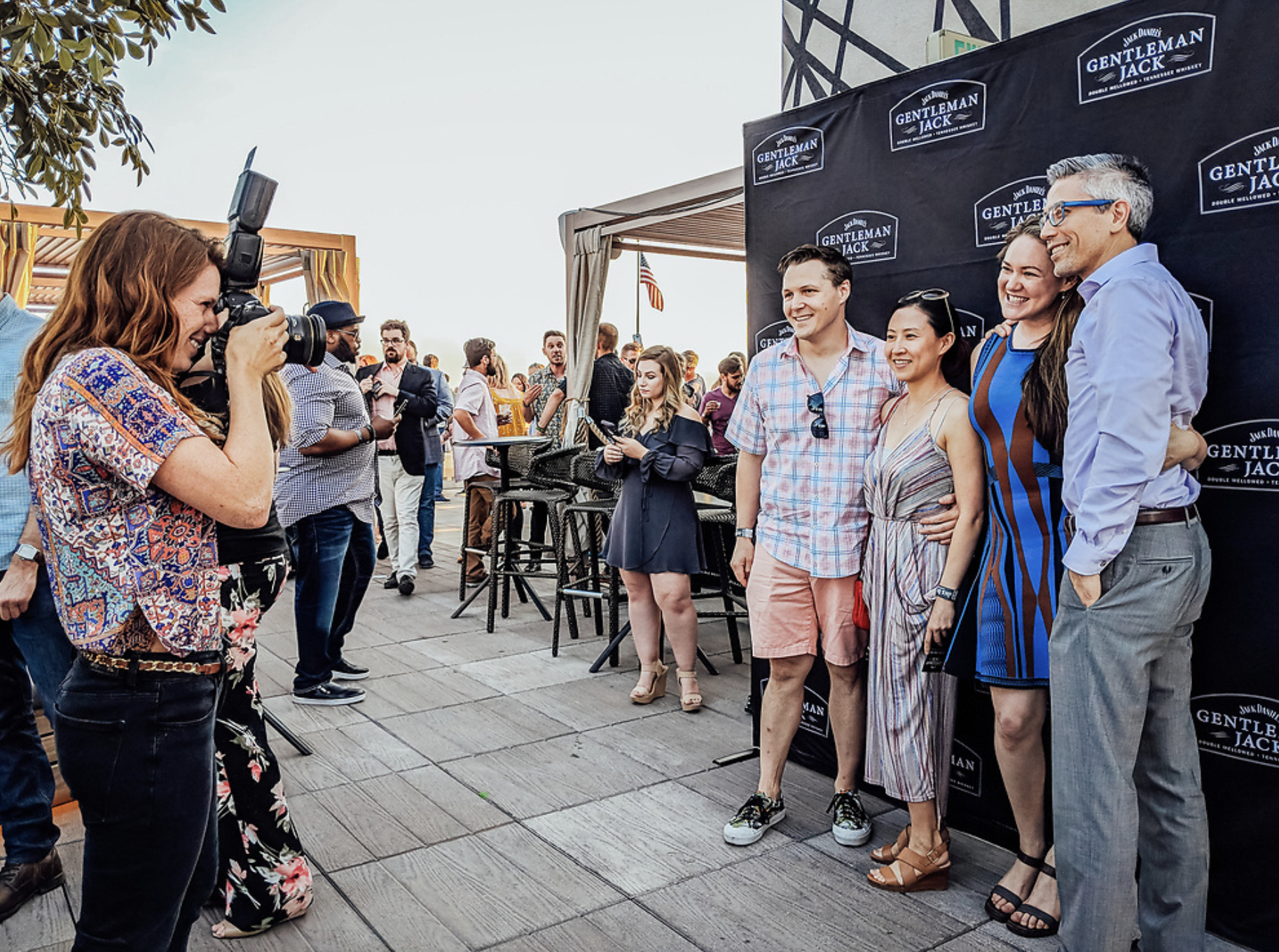 Rebecca takes a photo of two men and two women at a rooftop bar event