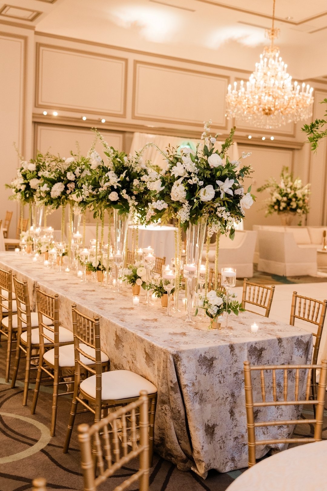 Family tables set with tall arrangements, sprinklings of bud vases, and floating monet candles 🕯️