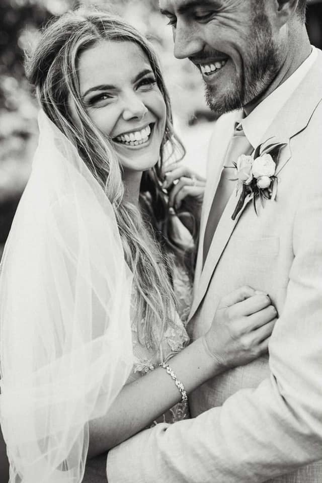 A bride and groom smiling at each other, close-up shot at their wedding, black-and-white photograph.
