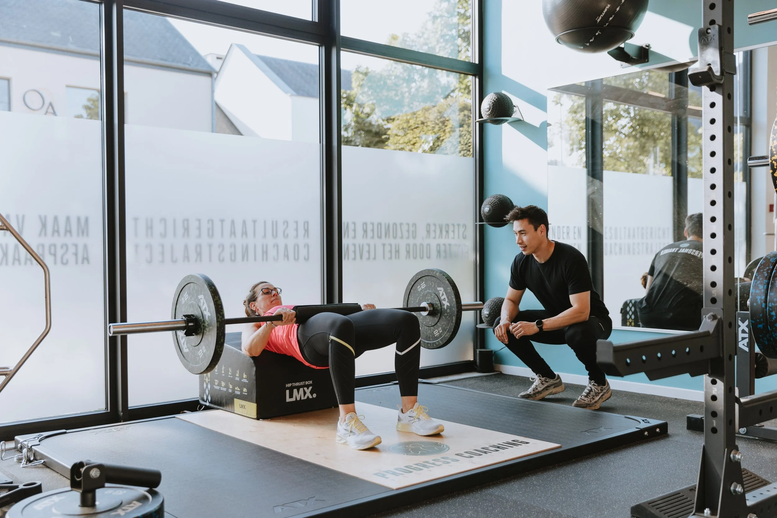 Krachttraining: Glenn begeleidt vrouw tijdens hip thrust voor bil- en beenspieren
