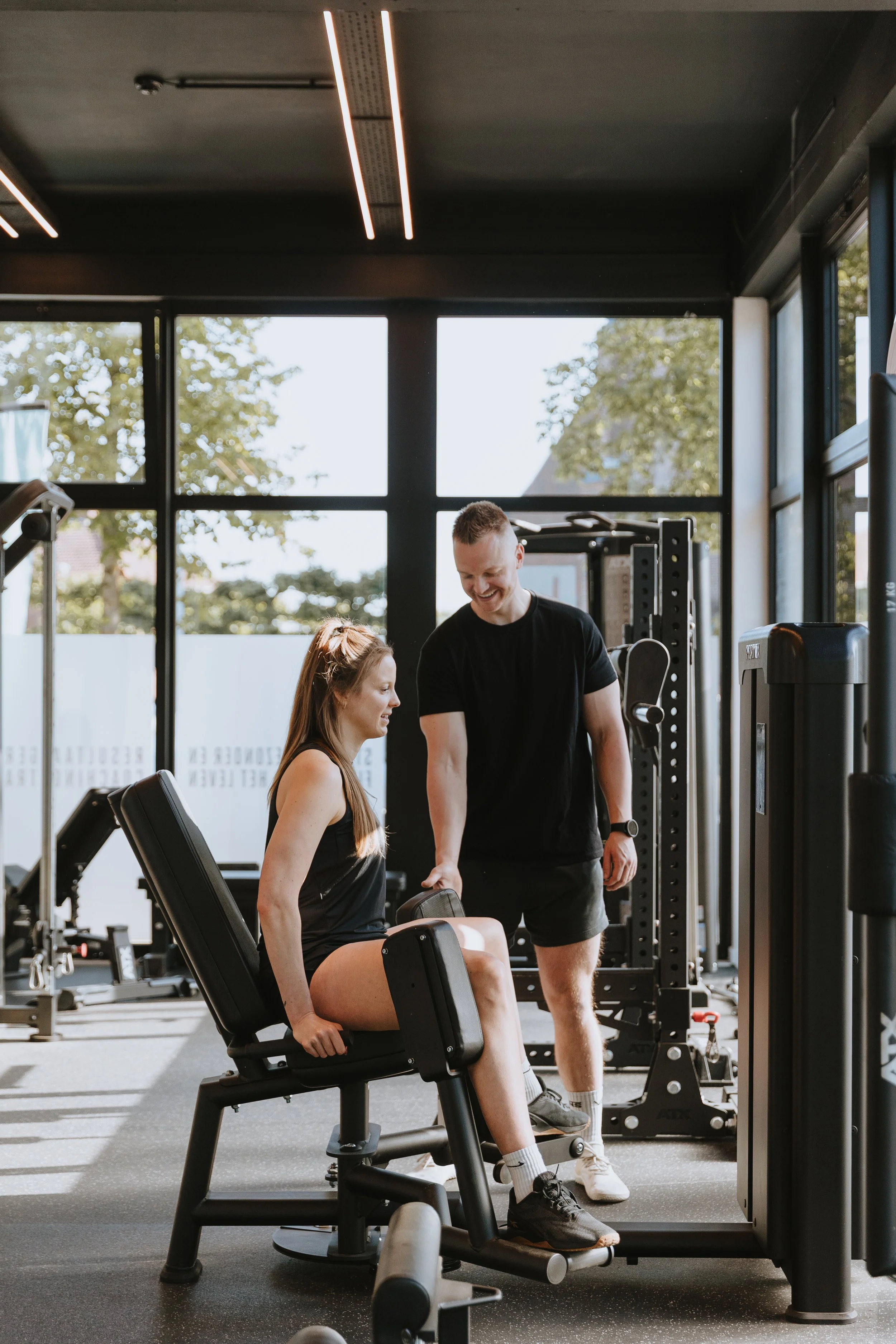 Een vrouw in sportschool krijgt instructies van een personal trainer tijdens een fitnessoefening.