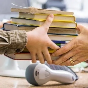 A stack of books being passed from hand to hand over a library desk