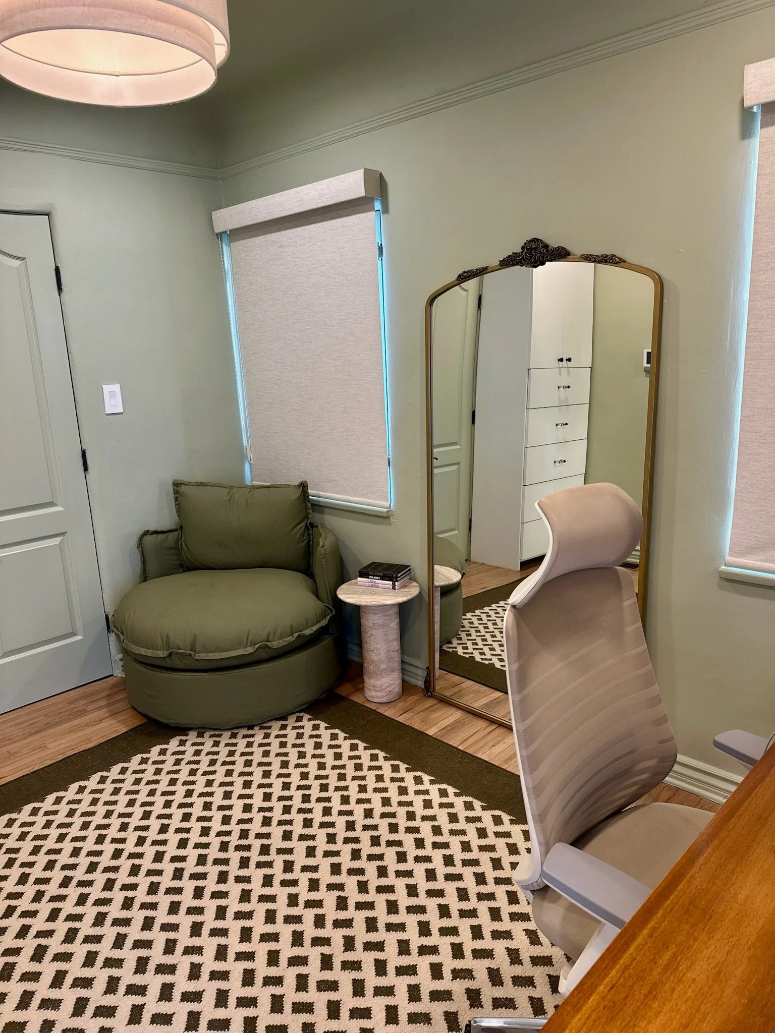 Rachel Neporents therapy office in Los Angeles with desk, desk chair as well as a mirror and green arm chair in the background