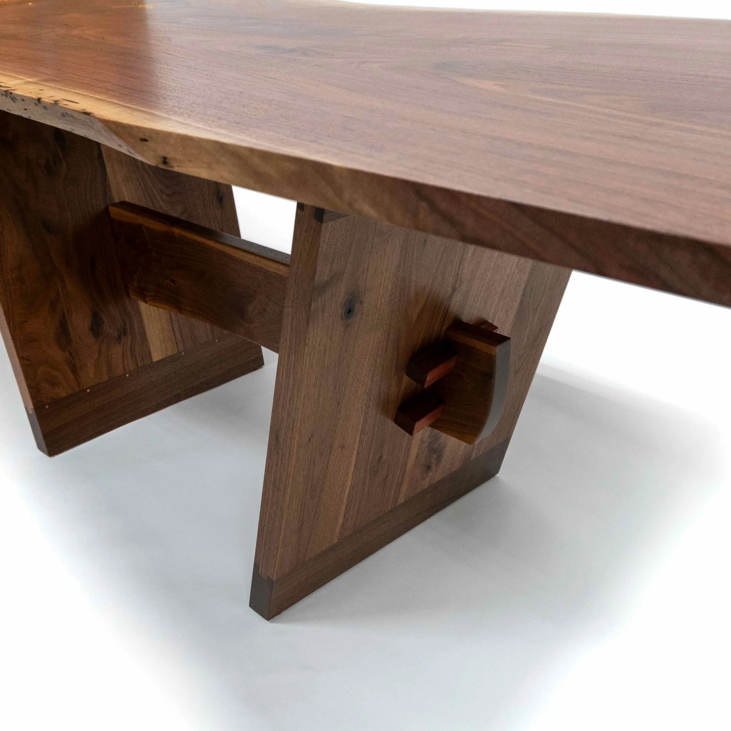 Evocatus dining table in black walnut slab and walnut timber with bubinga and gold leaf, view of the trestle.