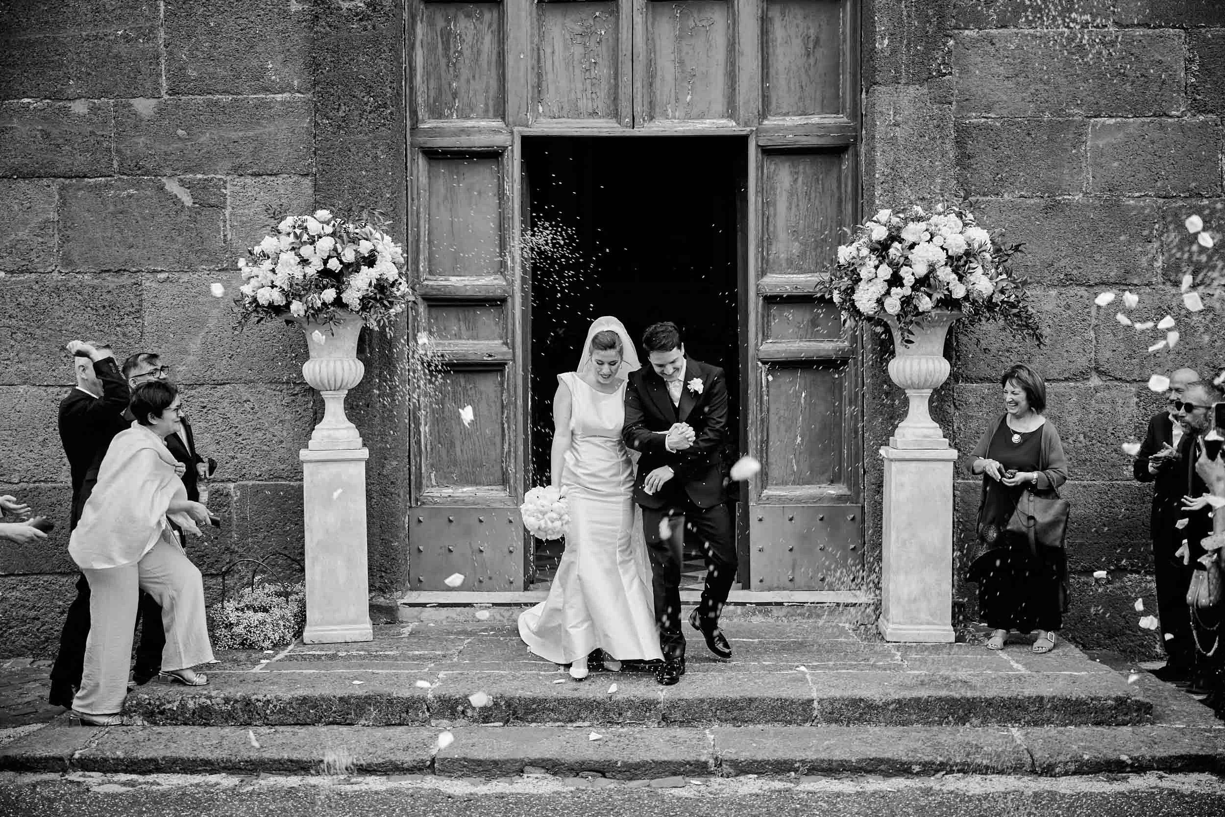 Rice flying everywhere as the couple exits the church — black and white.