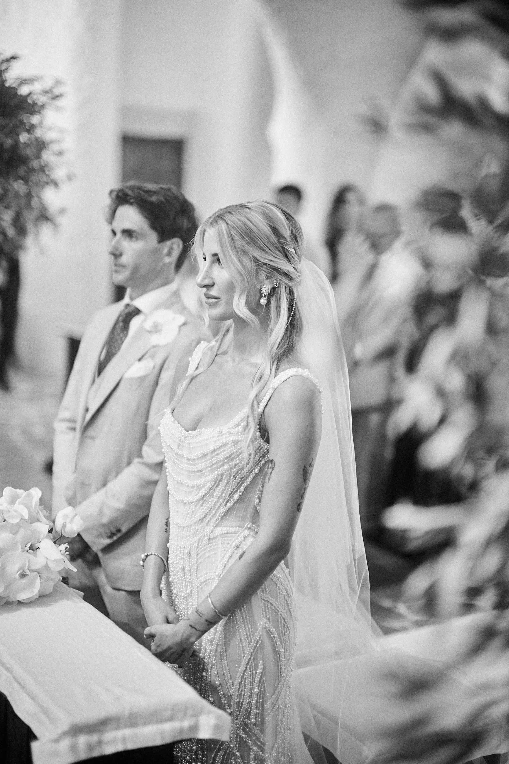 Bride and groom during the wedding ceremony in Sardinia, black and white portrait with the bride in focus.
