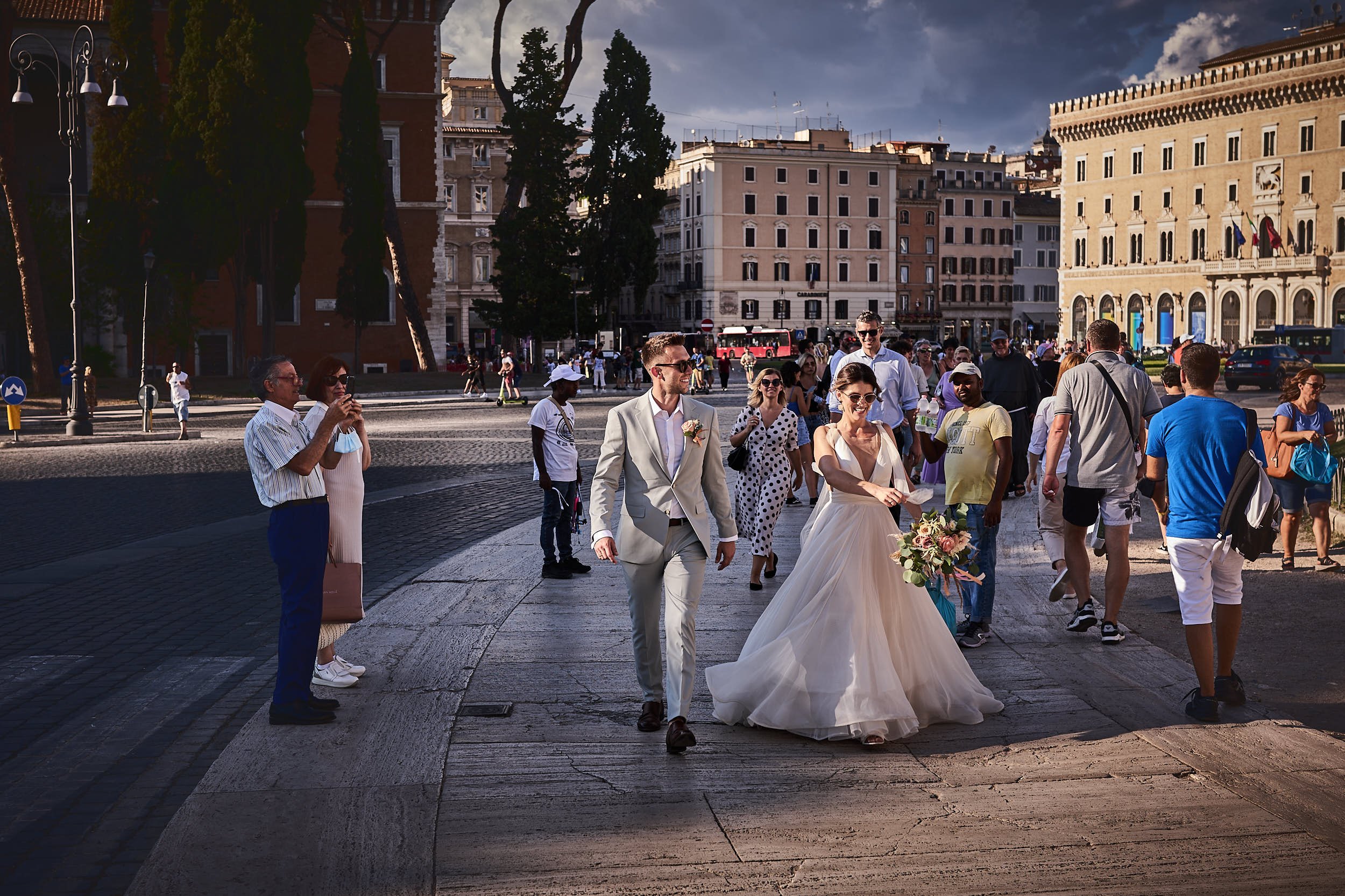 Bride and Groom walking in Piazza Venezia. A lot of tourist around them