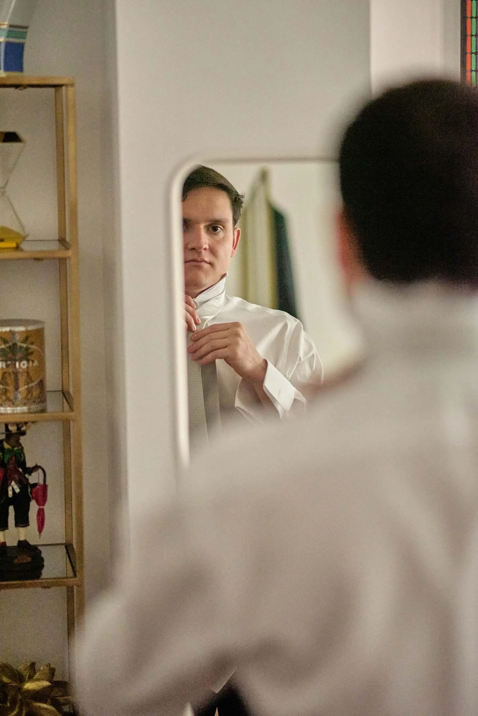 Groom getting ready, reflected in the mirror.