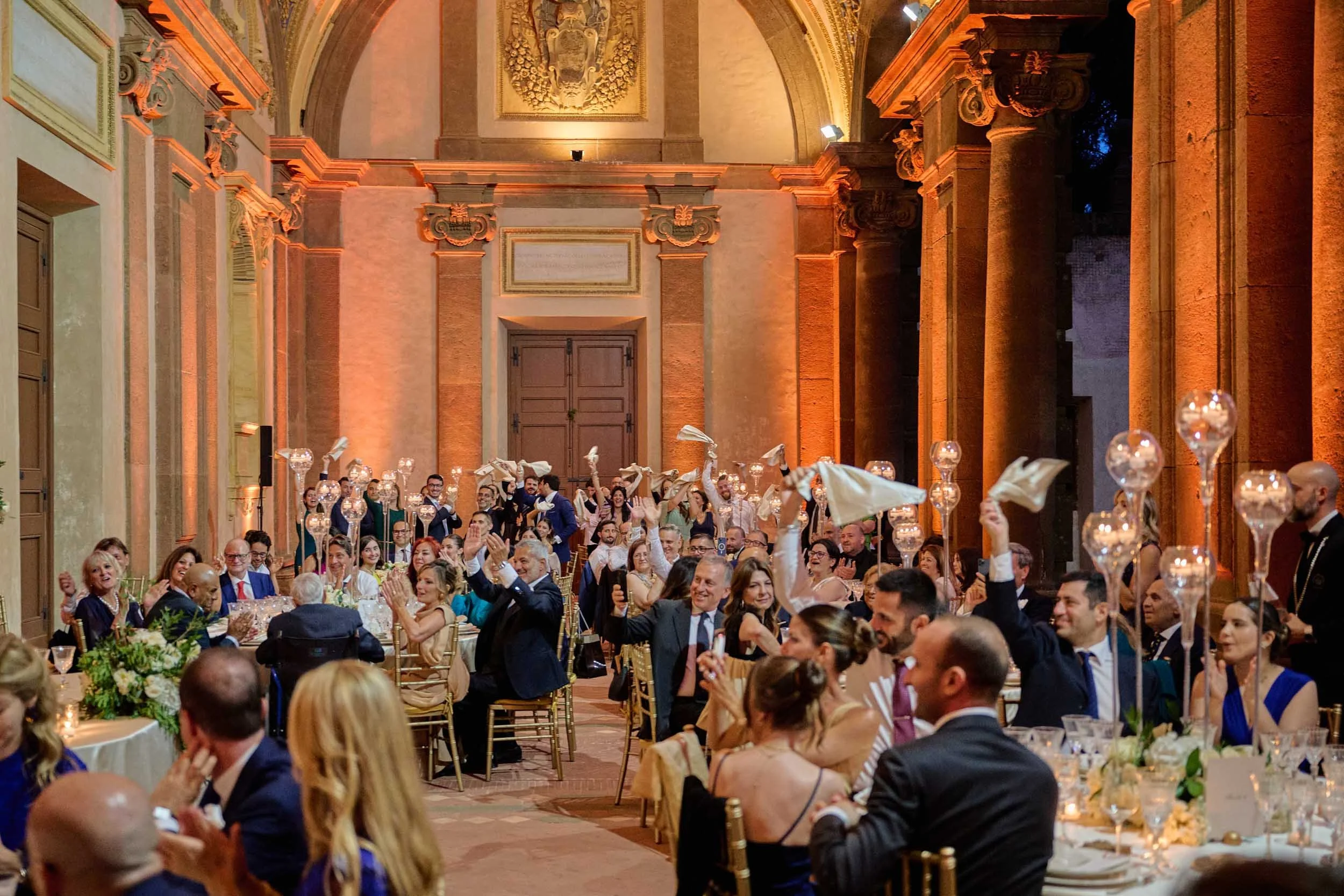 Smiling guests spin handkerchiefs in the air to greet the couple.