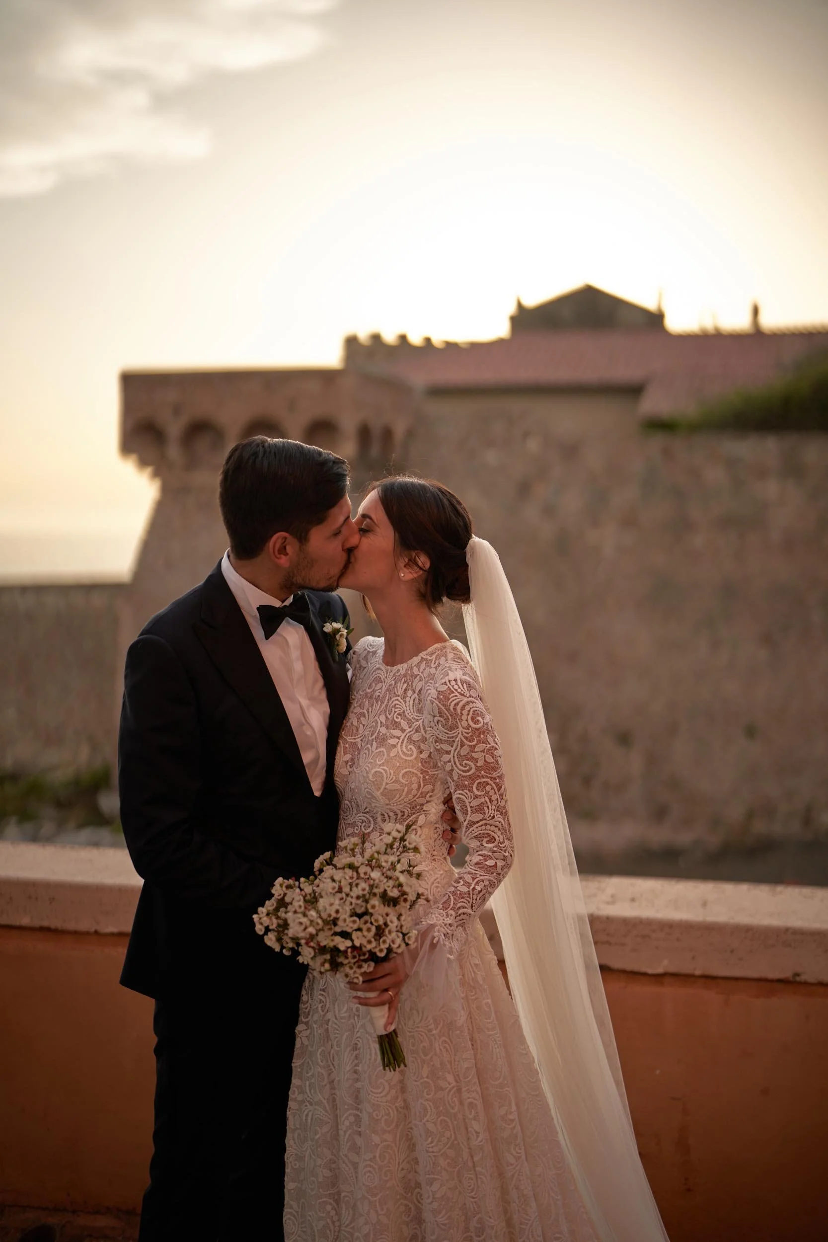Bride and groom kissing at sunset at Hotel Posta Vecchia on the Lazio coast, Italy