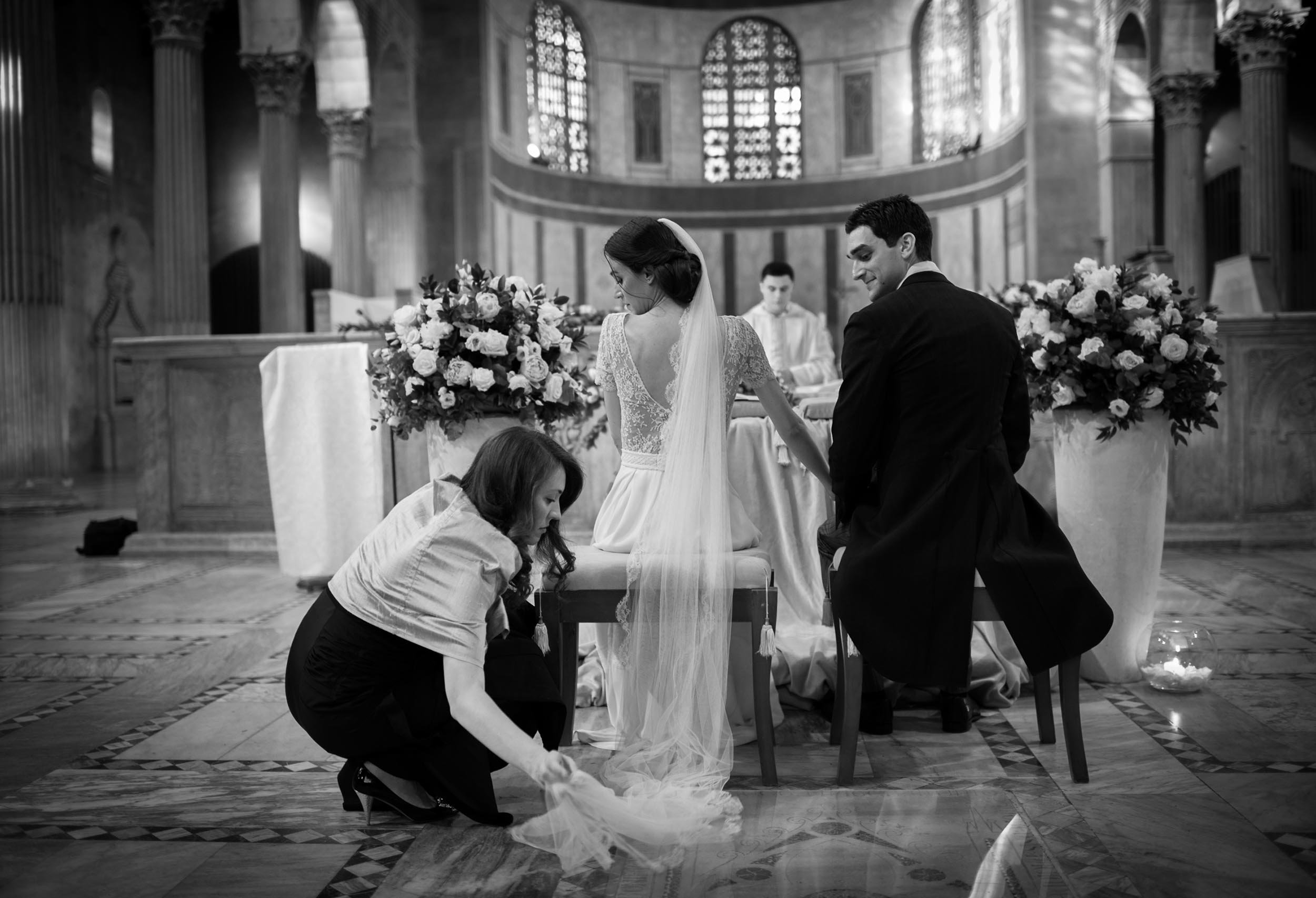The Maid of Honor arranges the bride's veil in the church. Black and White