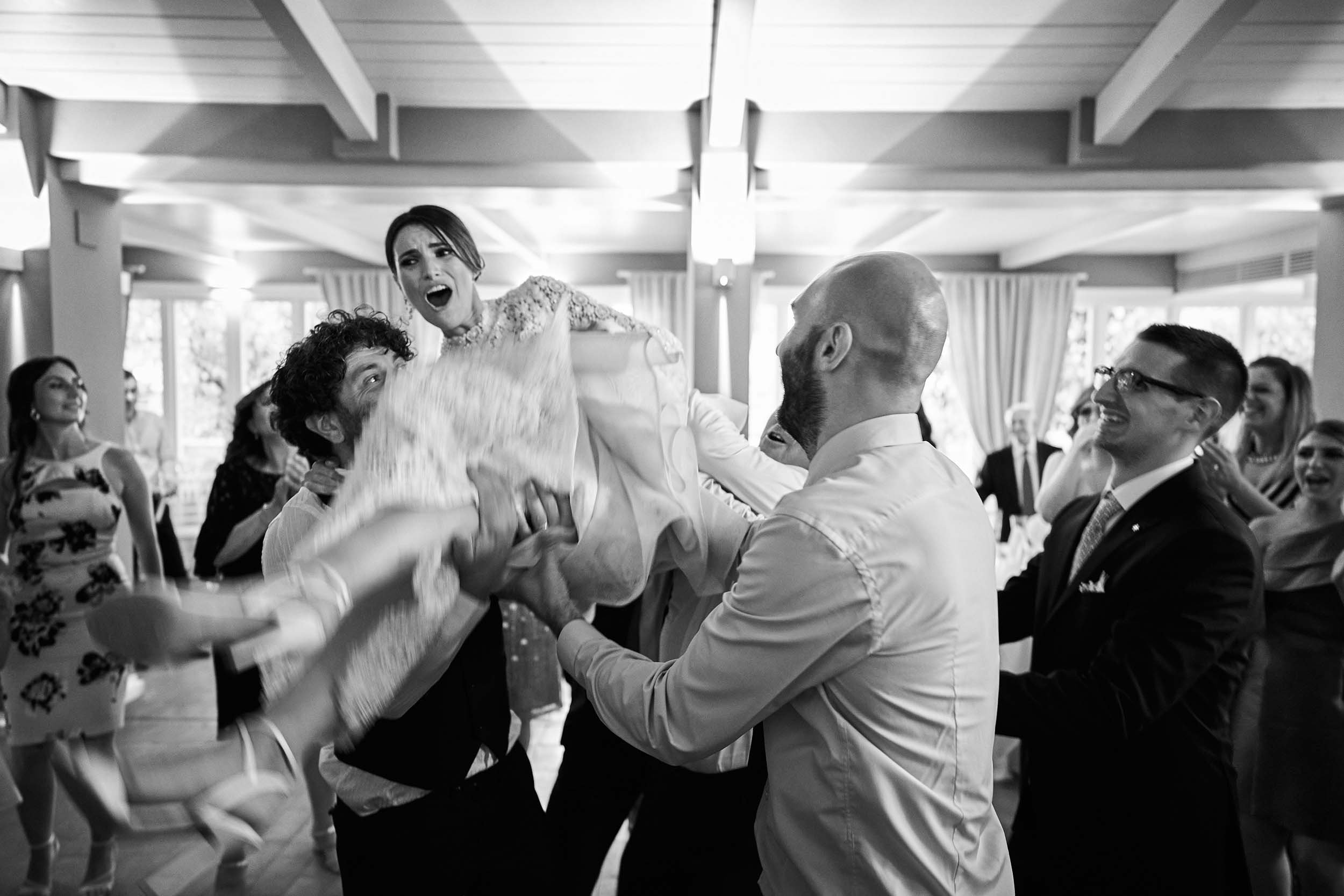 Guests lifting the bride during the dances, black and white.