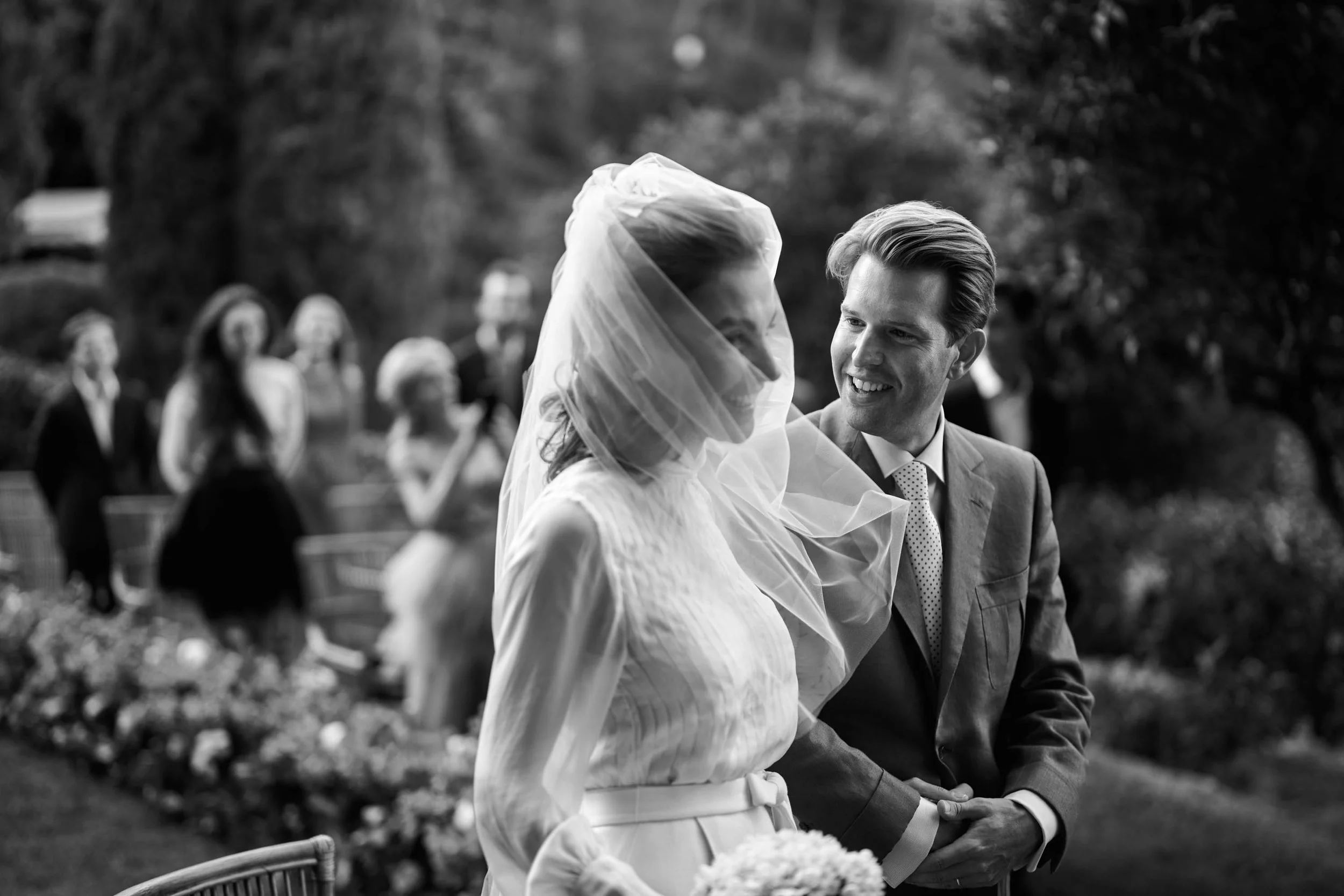 Intimate destination wedding in Italy — bride and groom smiling as the veil moves in the wind (black and white).