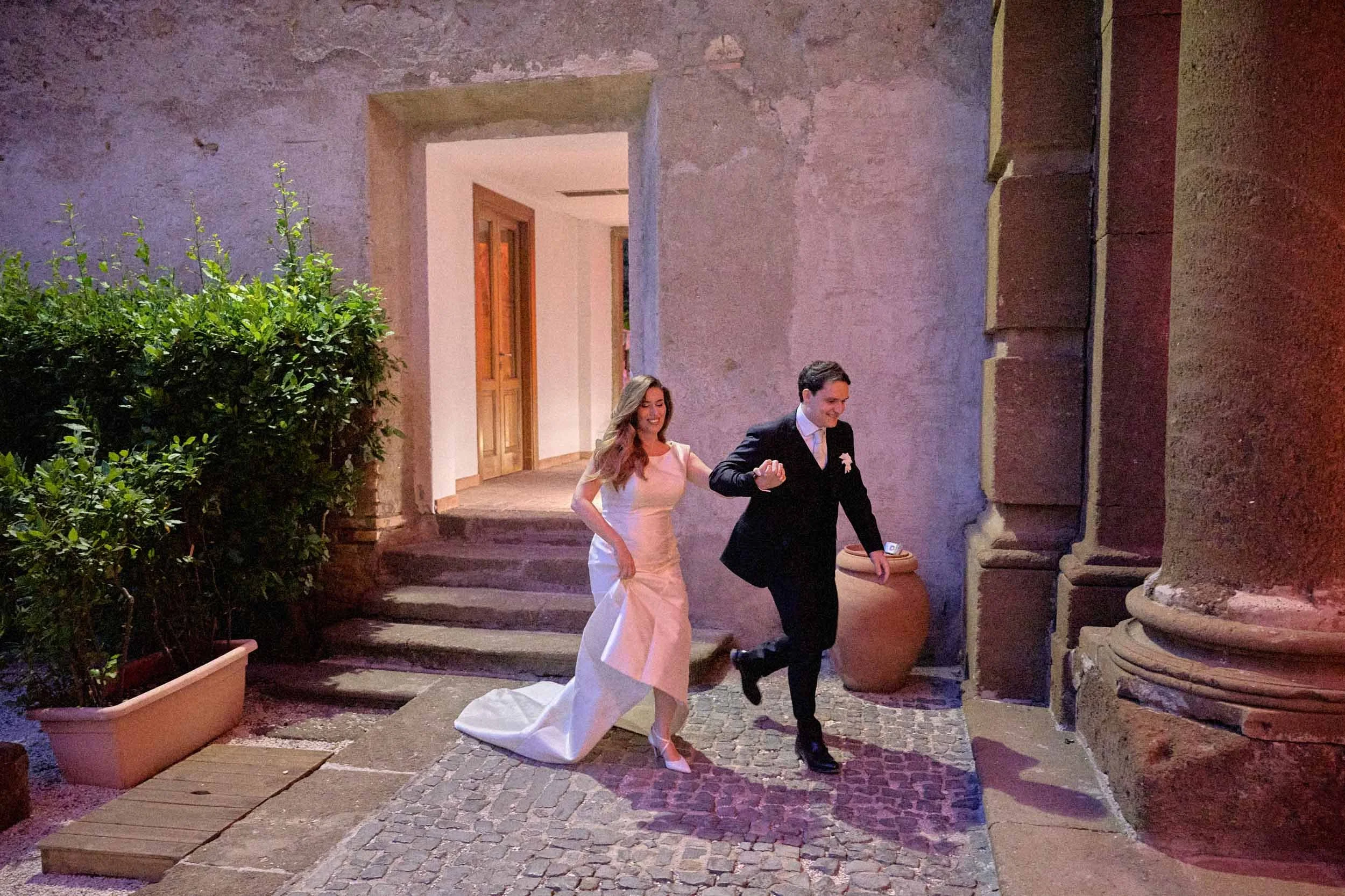 Bride and groom sprint into the room, smiling and happy.