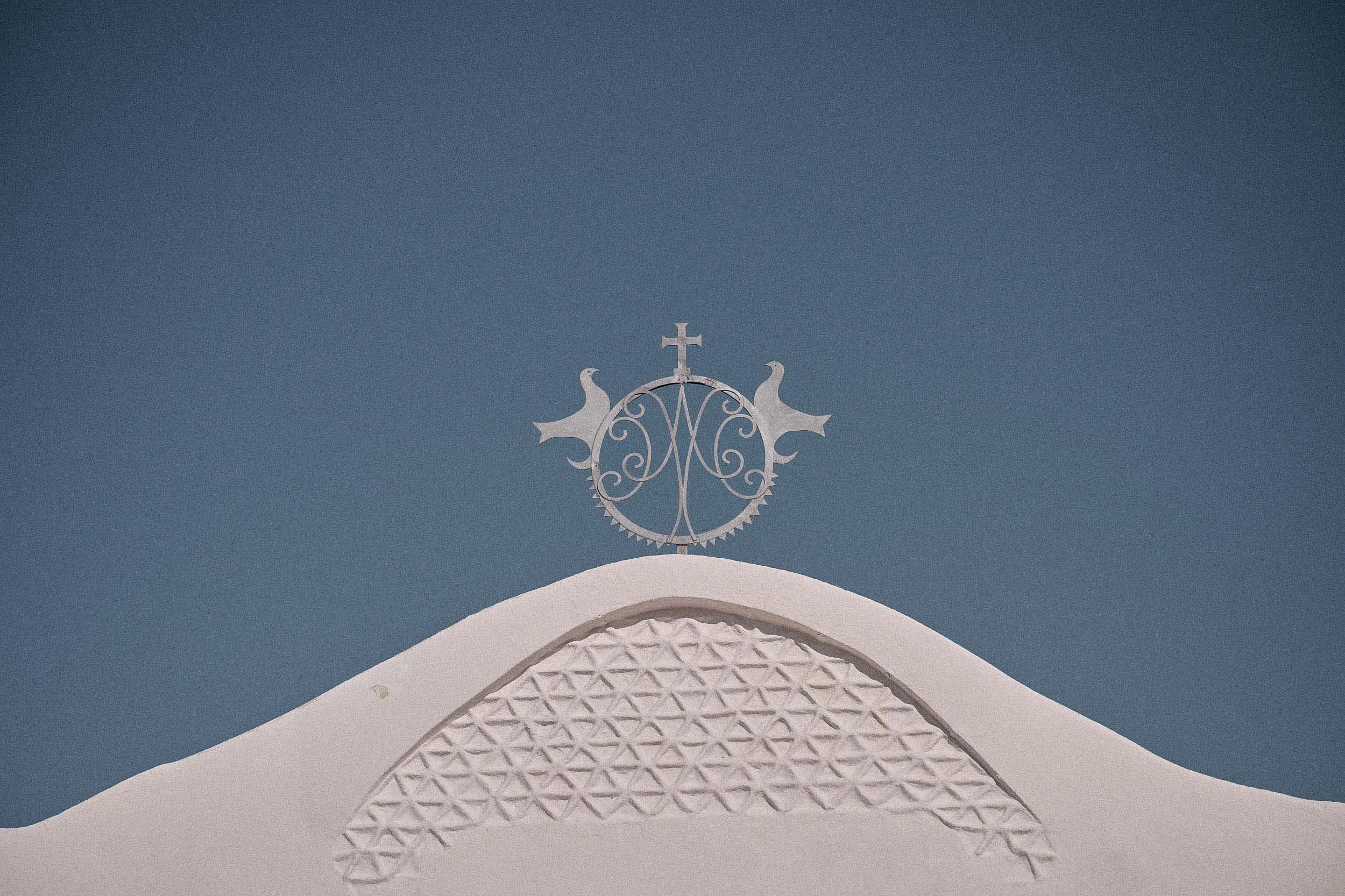 Detail of a church facade with a crest on a blue wall in Porto Cervo, Sardinia.