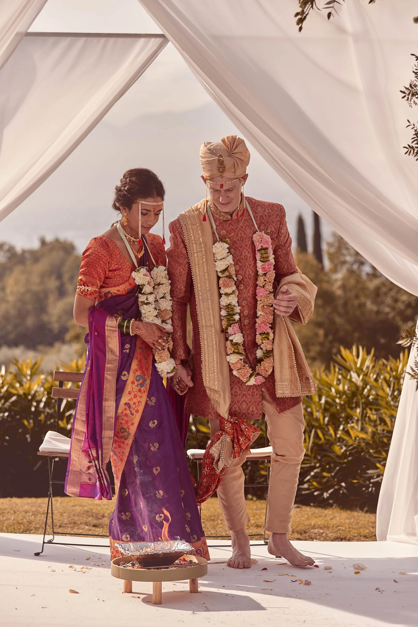 Bride and groom complete a ceremony ritual together around the fire — Indian wedding in Tuscany
