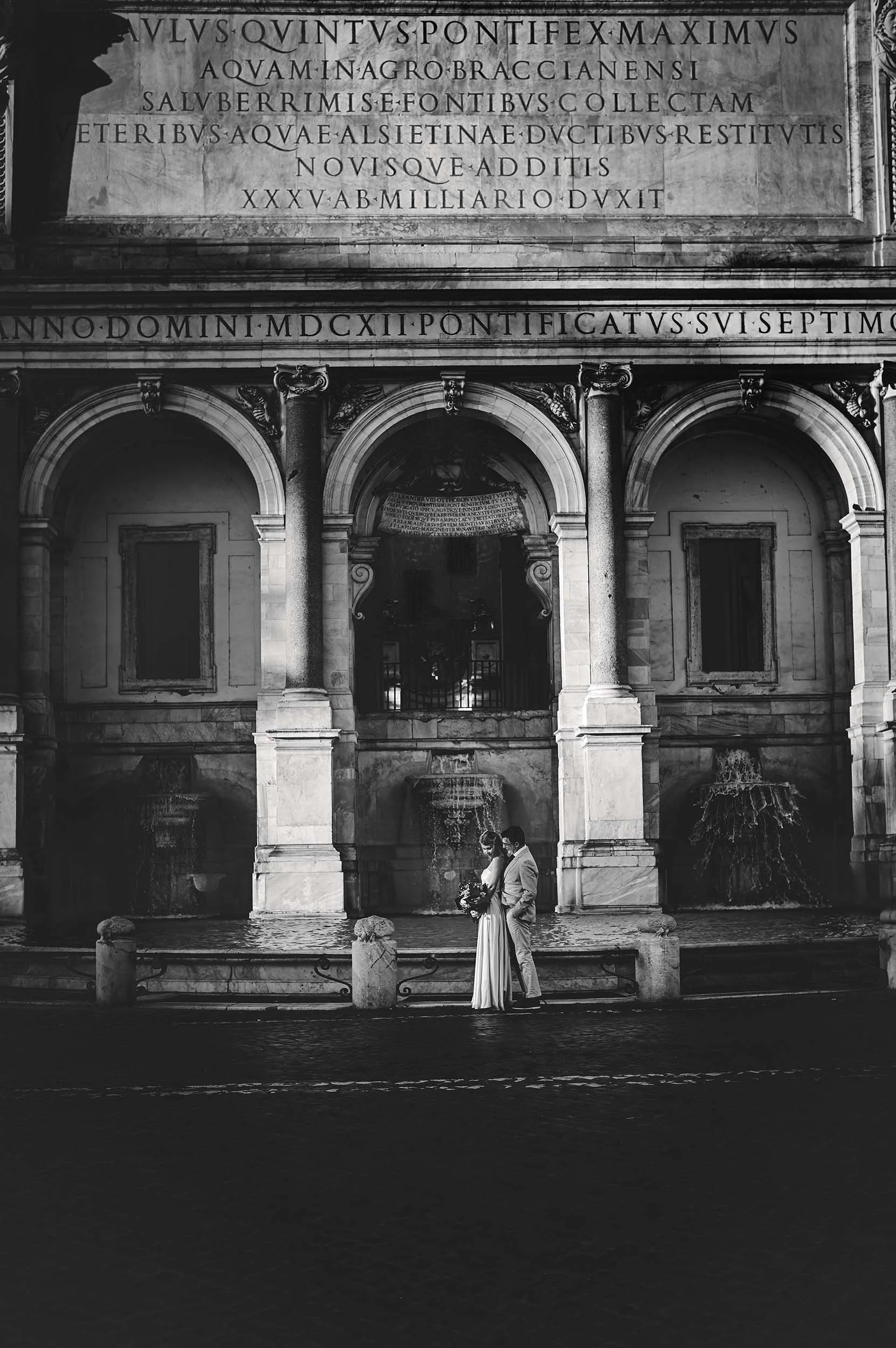 Bride and groom walking in front of Fontana Dell'Acqua Paola, Rome, Italy. Black and White