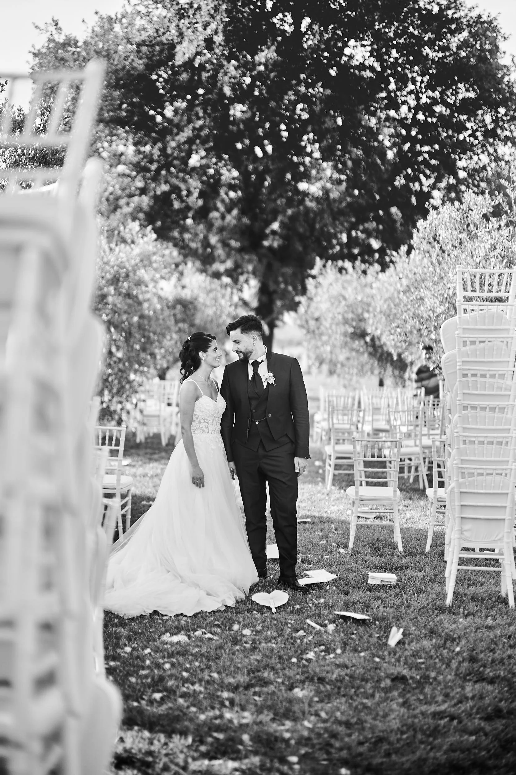 Bride and groom among empty chairs after the ceremony, quiet documentary wedding portrait.