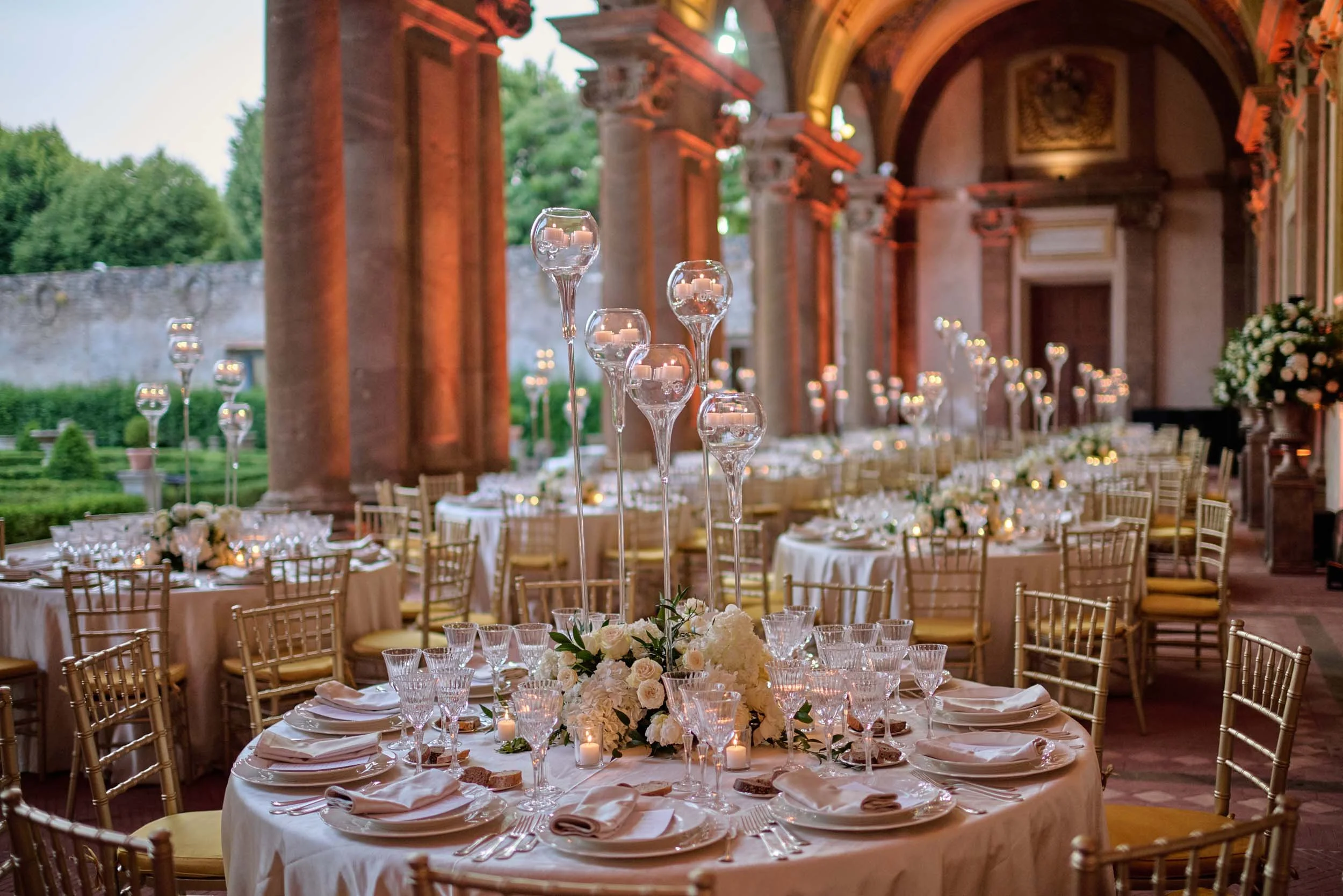 Glowing candles on wedding dinner tables in Villa Mondragone’s courtyard.