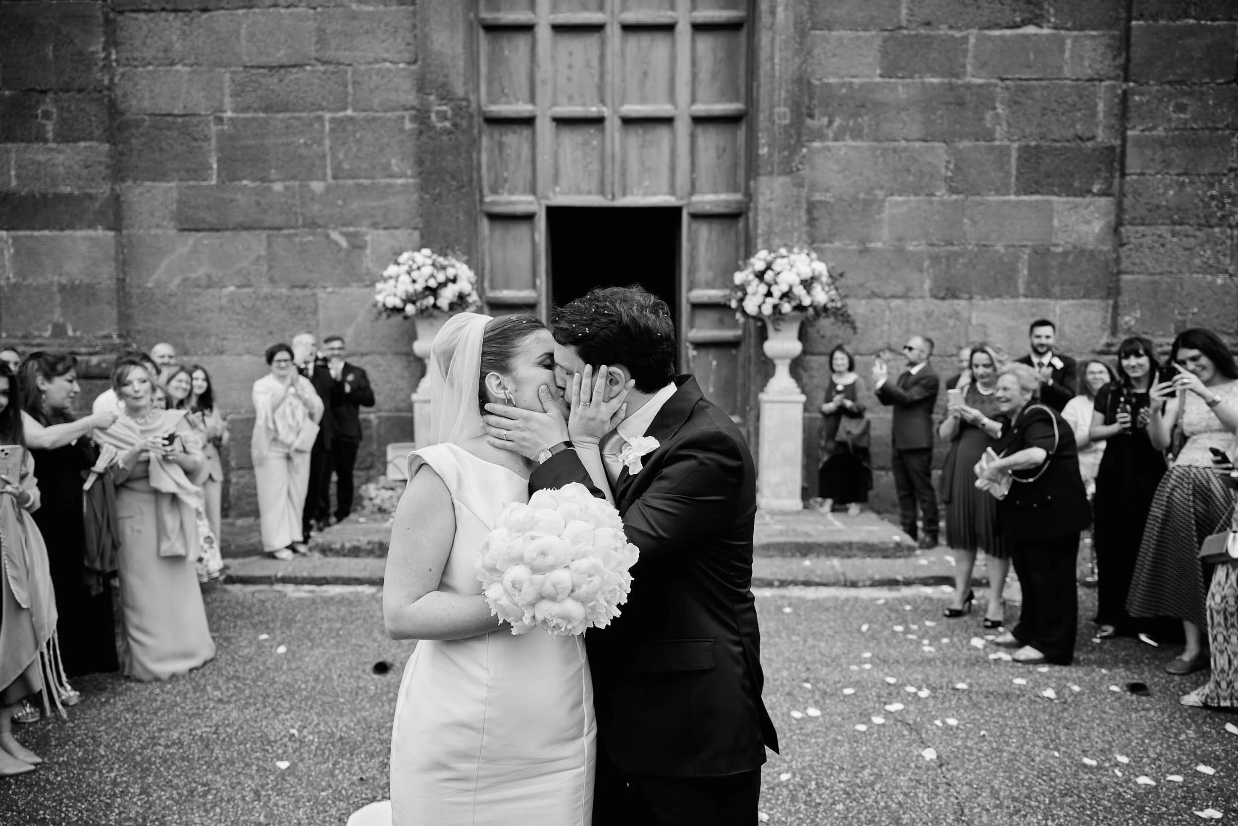 Newlyweds kiss in front of the church just after the rice toss.