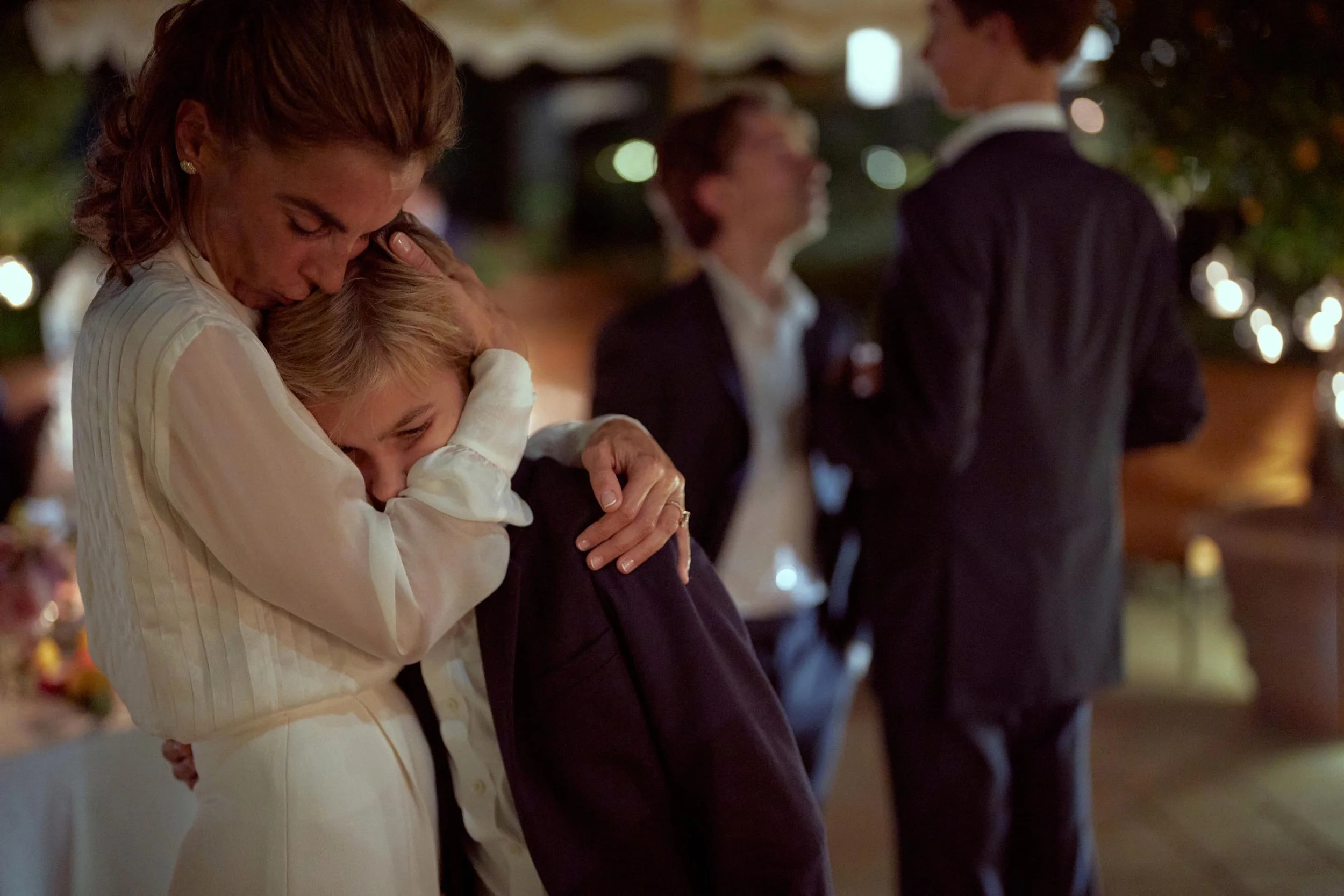 Destination wedding in Italy at Hotel Il Pellicano — bride and her son embrace during the evening celebration.