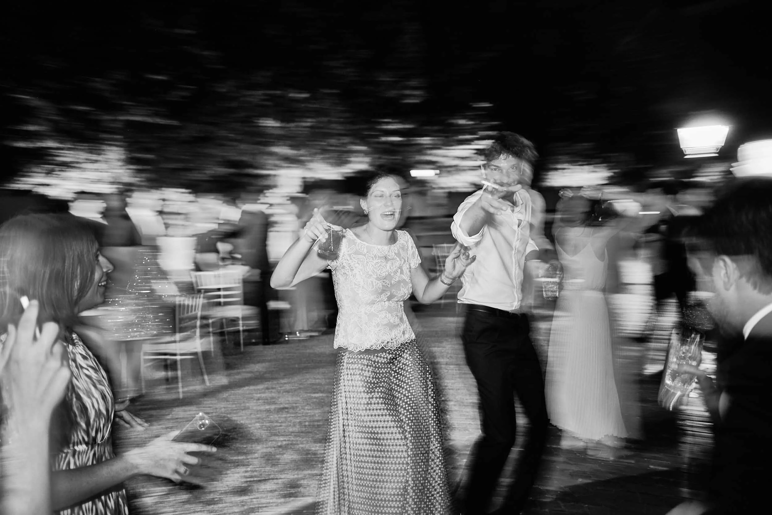Black-and-white, motion-blurred and out-of-focus photo of guests dancing at the wedding.