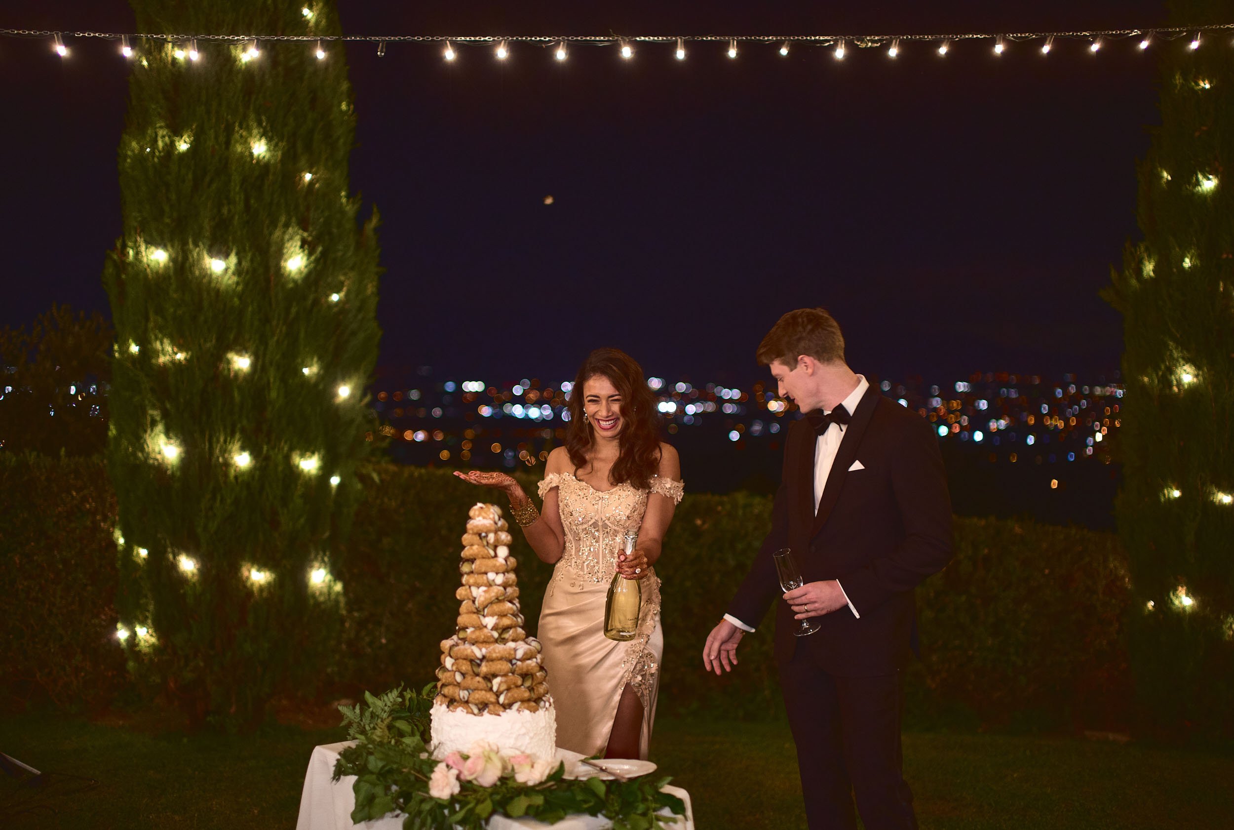 Bride and groom pop champagne by the cake — celebration during an intimate destination wedding in Tuscany