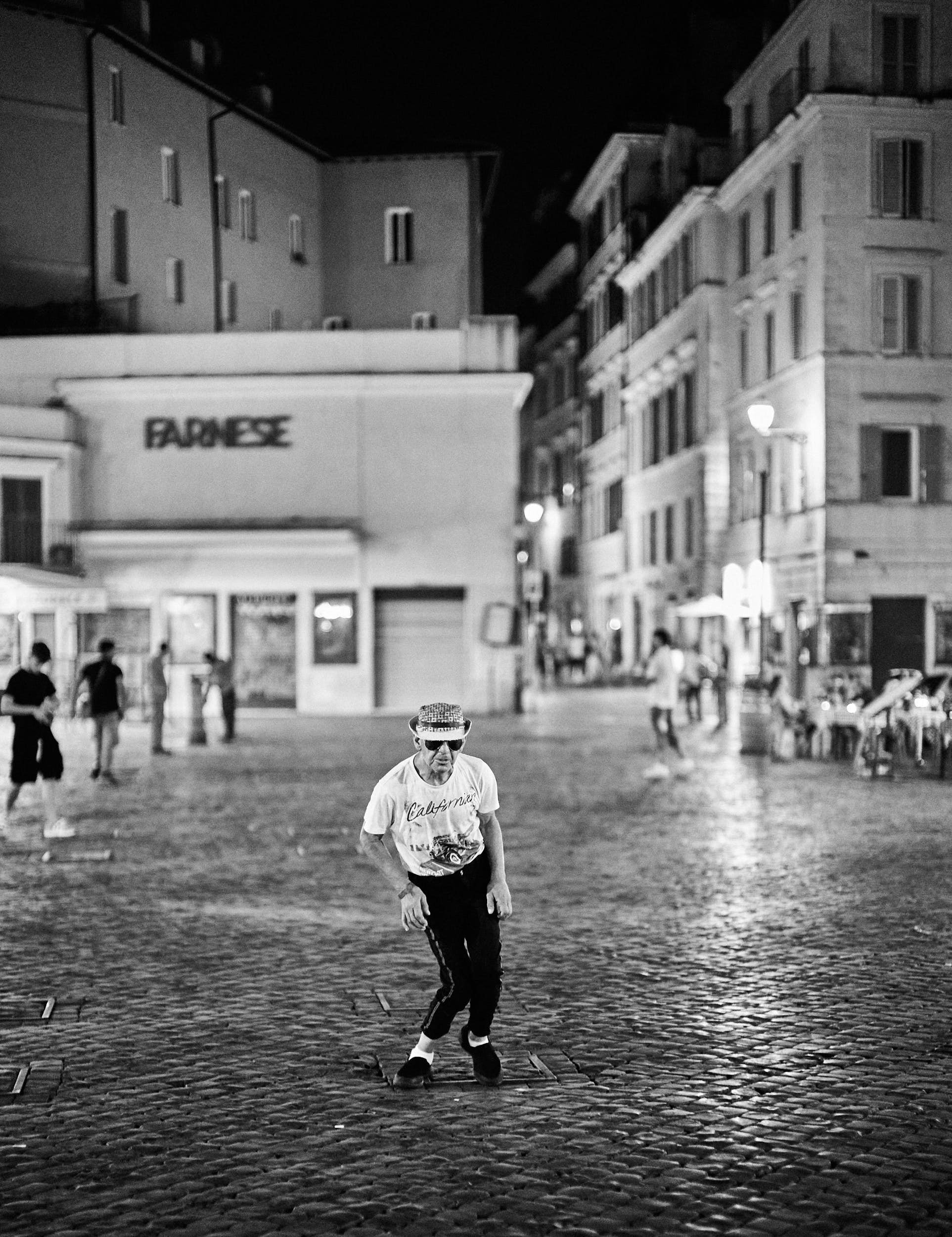 A man dancing in Campo de Fiori, Roma. Nighttime , in black and white.