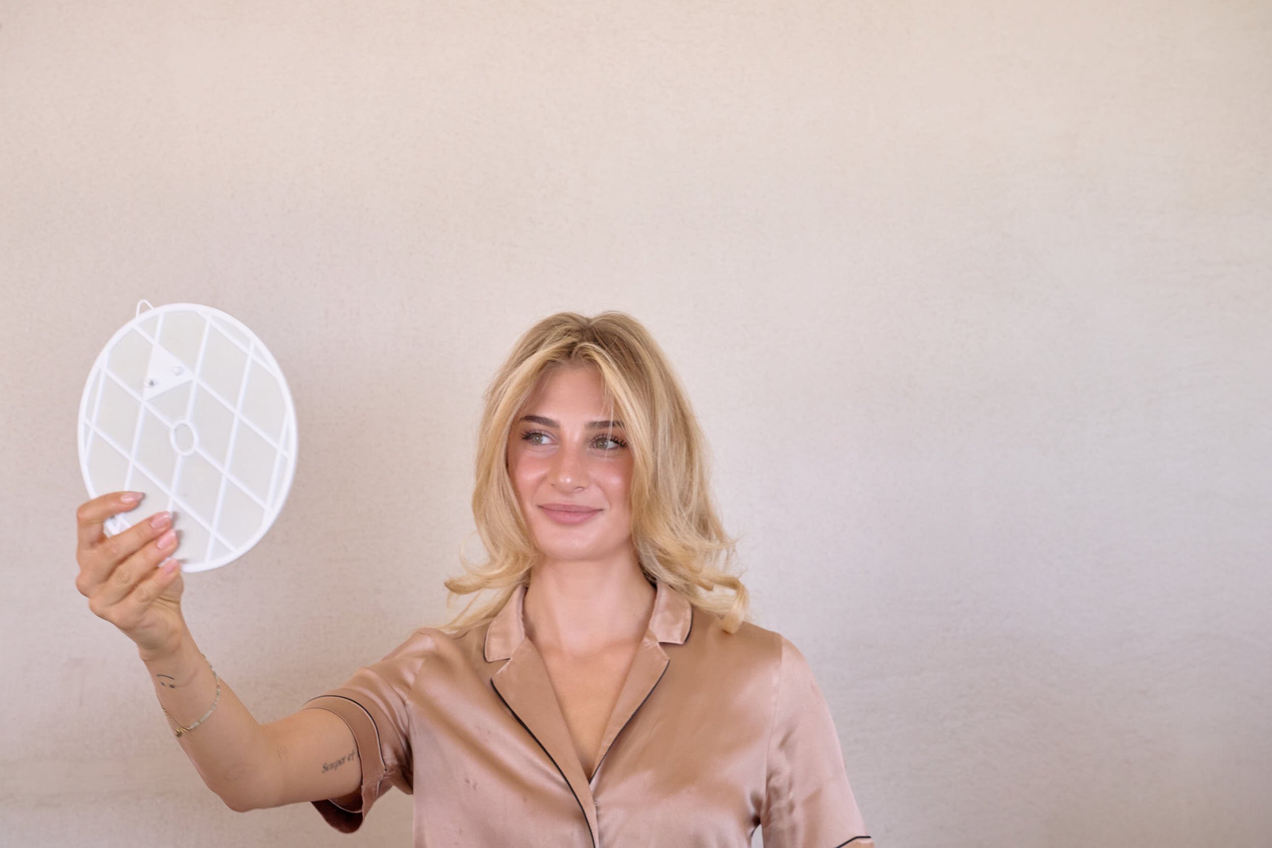 Wedding guest holding a handheld mirror during preparations at a private villa in Sardinia.