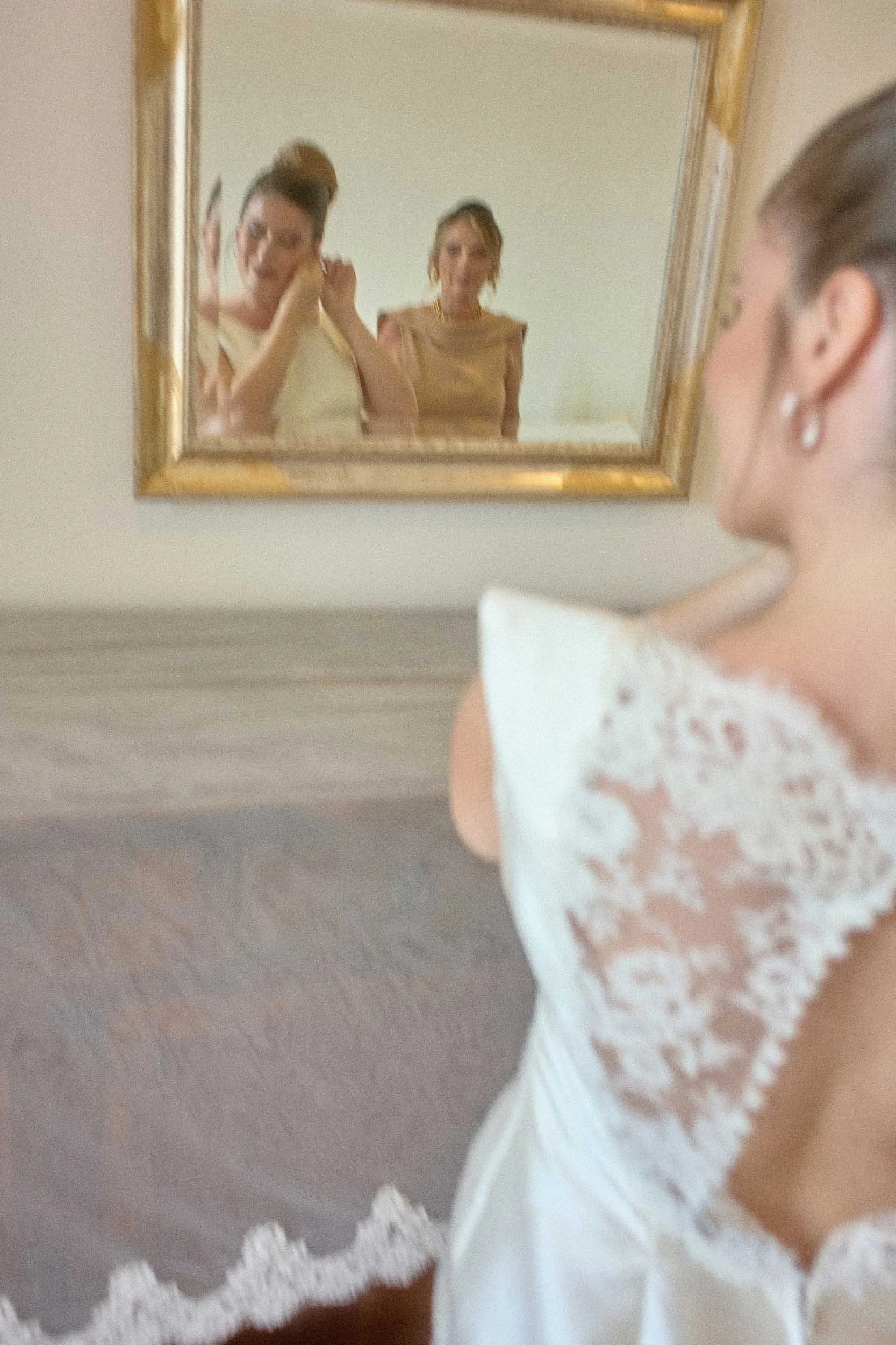 Motion-blurred, film-grain mirror reflection of the bride and her mother.