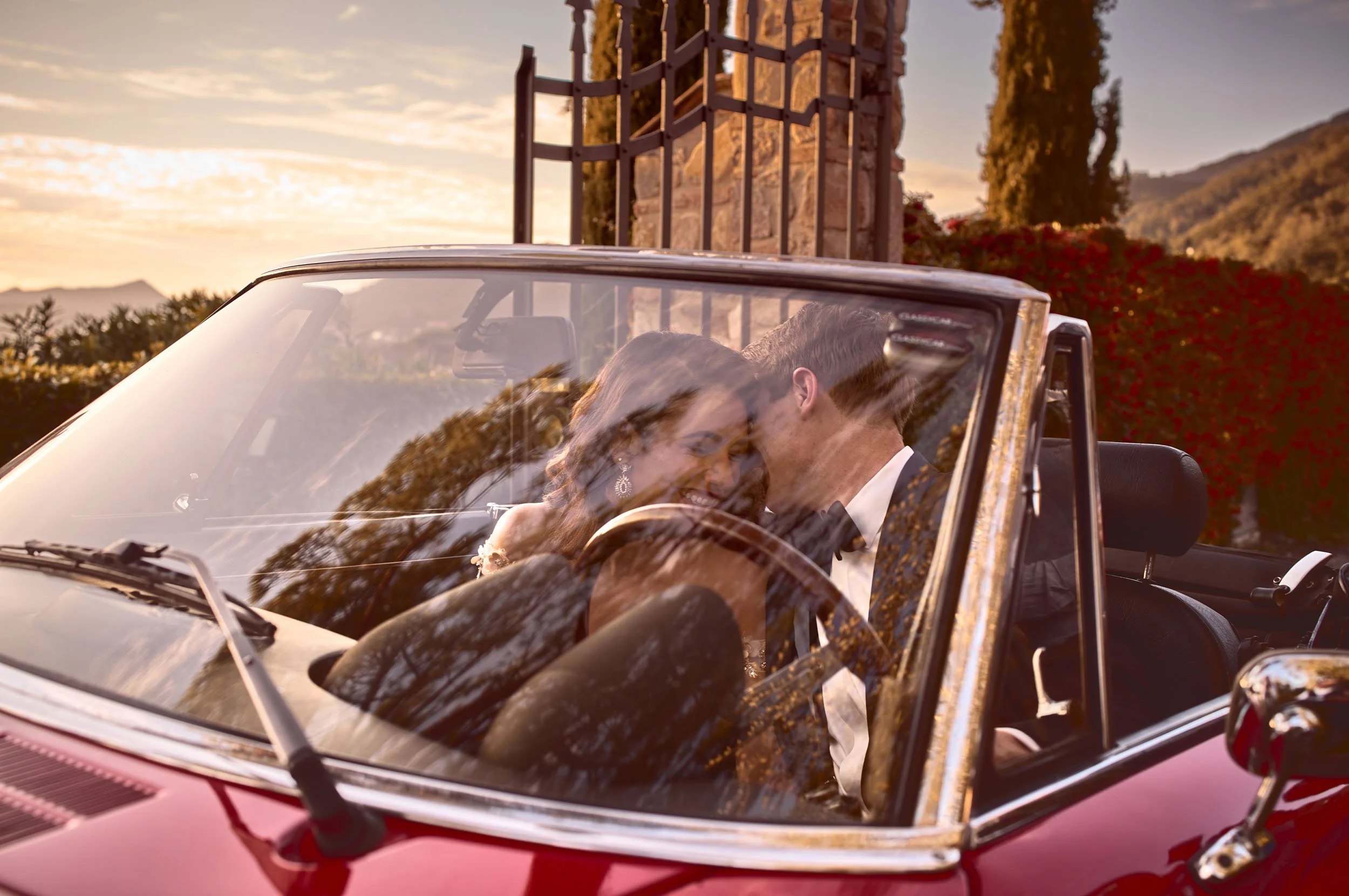 Groom whispers to the bride while arriving at the venue in a red Alfa Spider — Tuscany wedding weekend