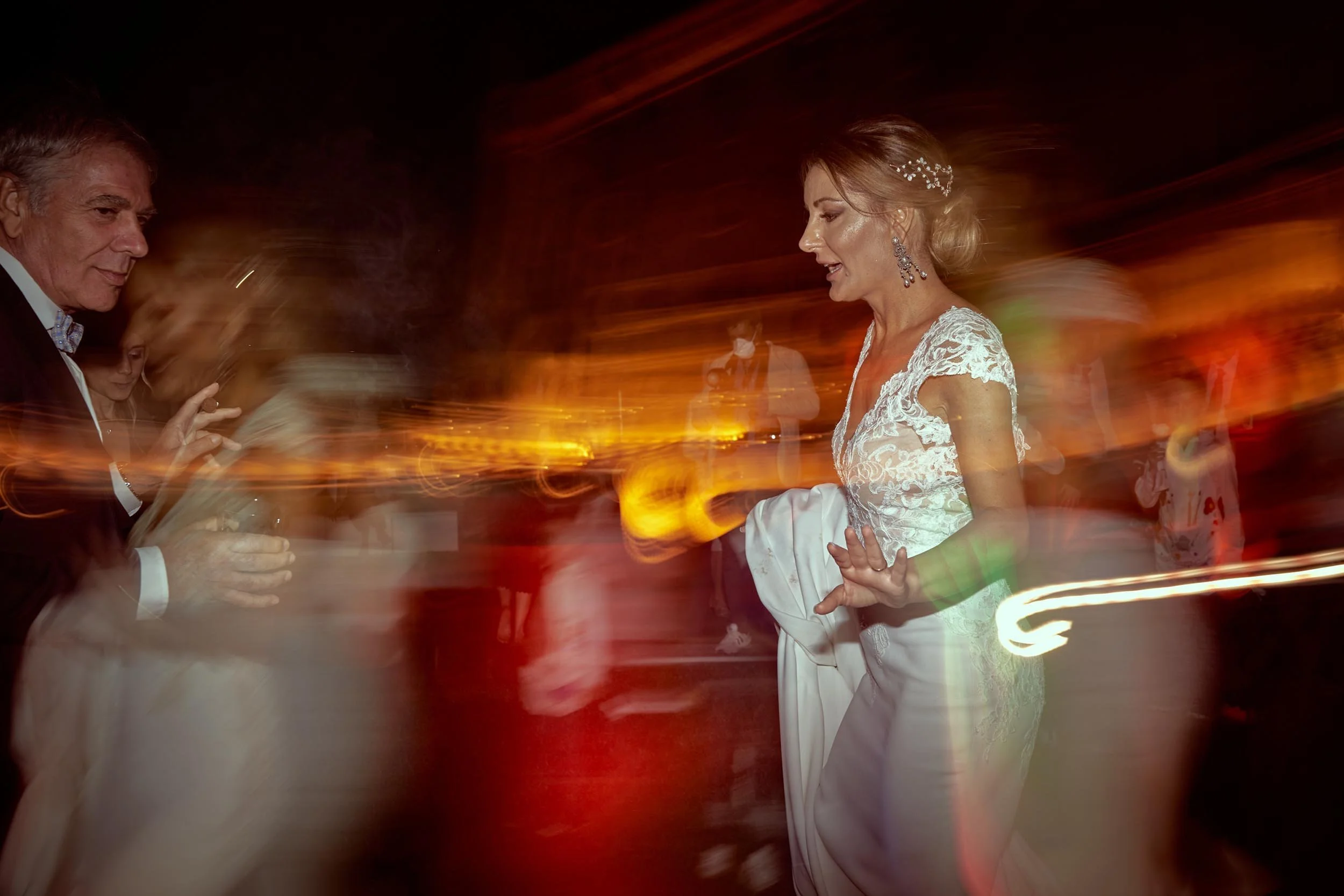 Artistic motion blur photograph of a bride dancing at night, showing energy and spontaneous joy. Editorial wedding photography style by NOVE100 in Rome."