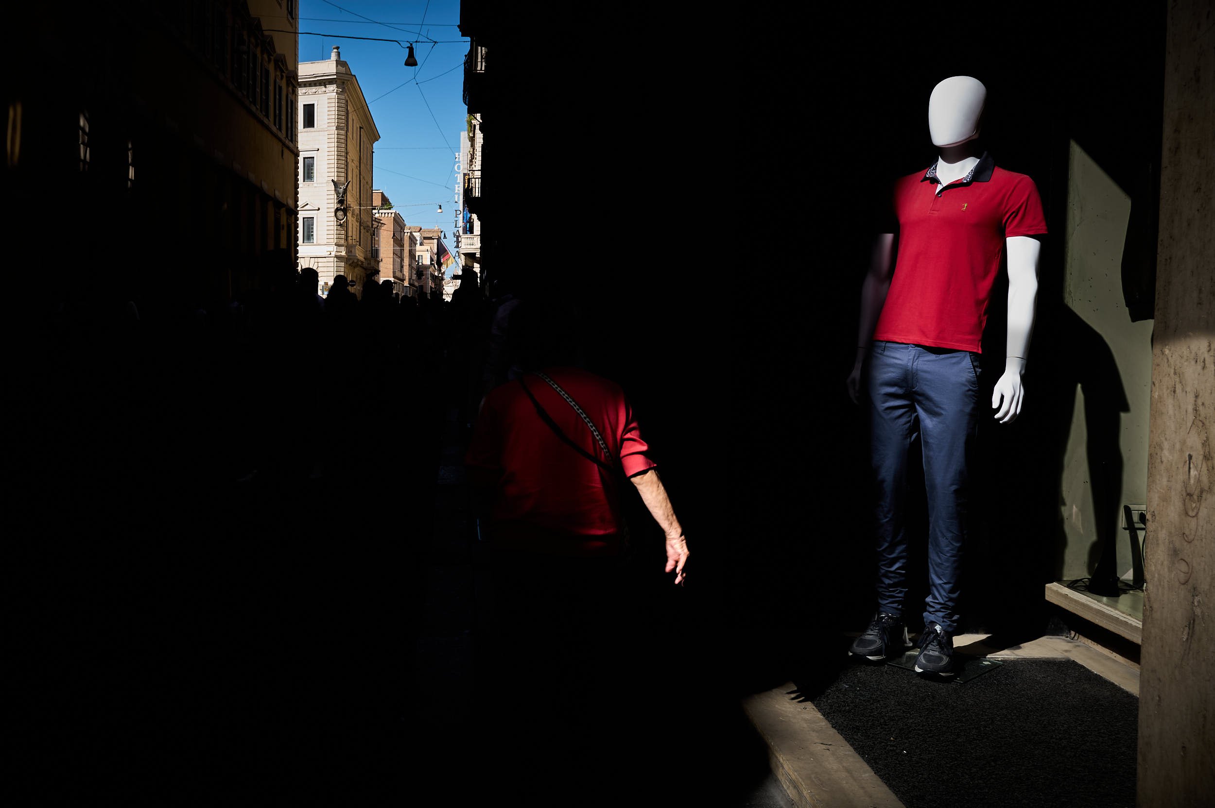 A woman with a red shirt walking near mannequin wearing a red shirt