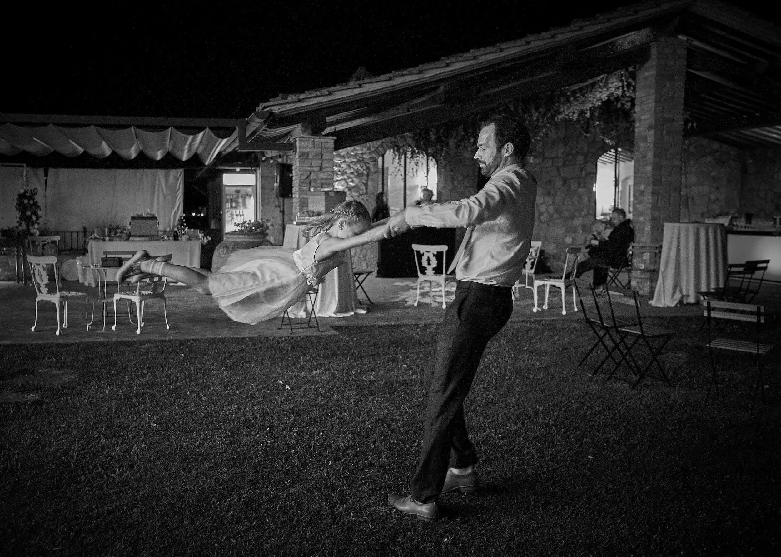 A family friend plays with the daughter, spinning her in the air