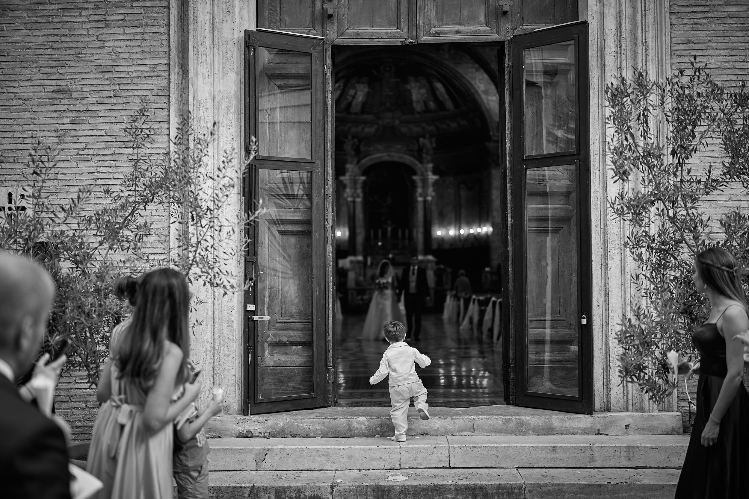 Little son going for the bride and the groom, while they're coming out of the church
