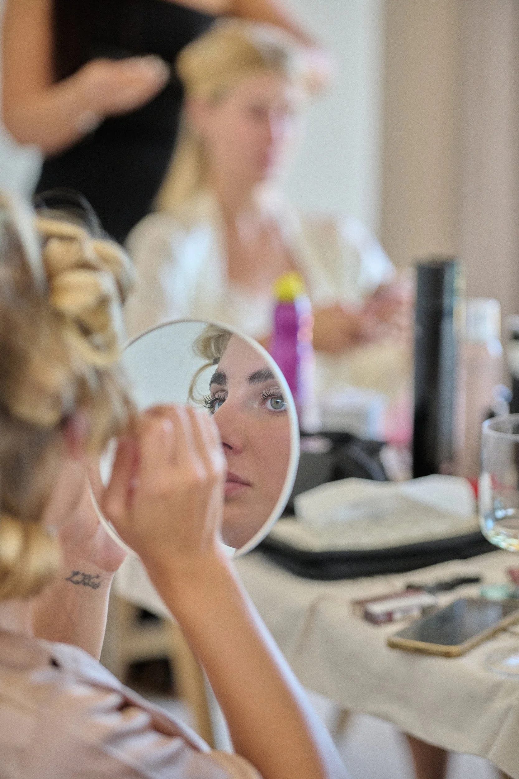 Makeup moment reflected in a handheld mirror during wedding preparations at a private villa .